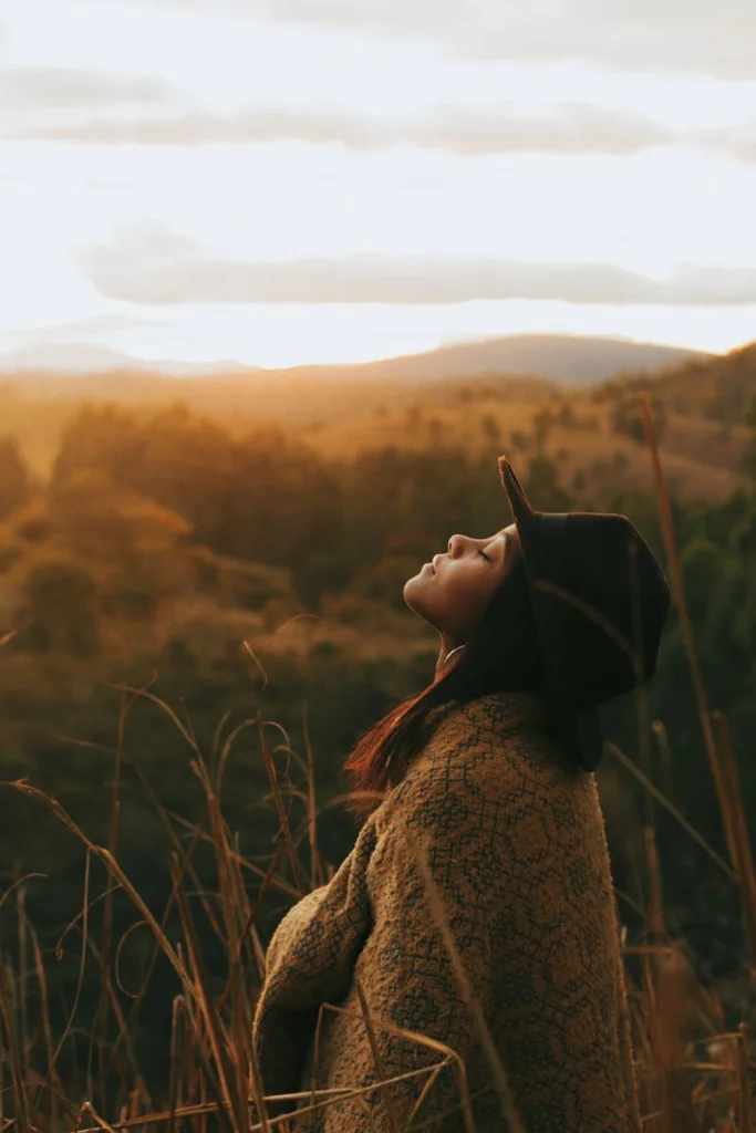 A woman in a hat relishes a peaceful sunset in Rio Vermelho's scenic landscape.