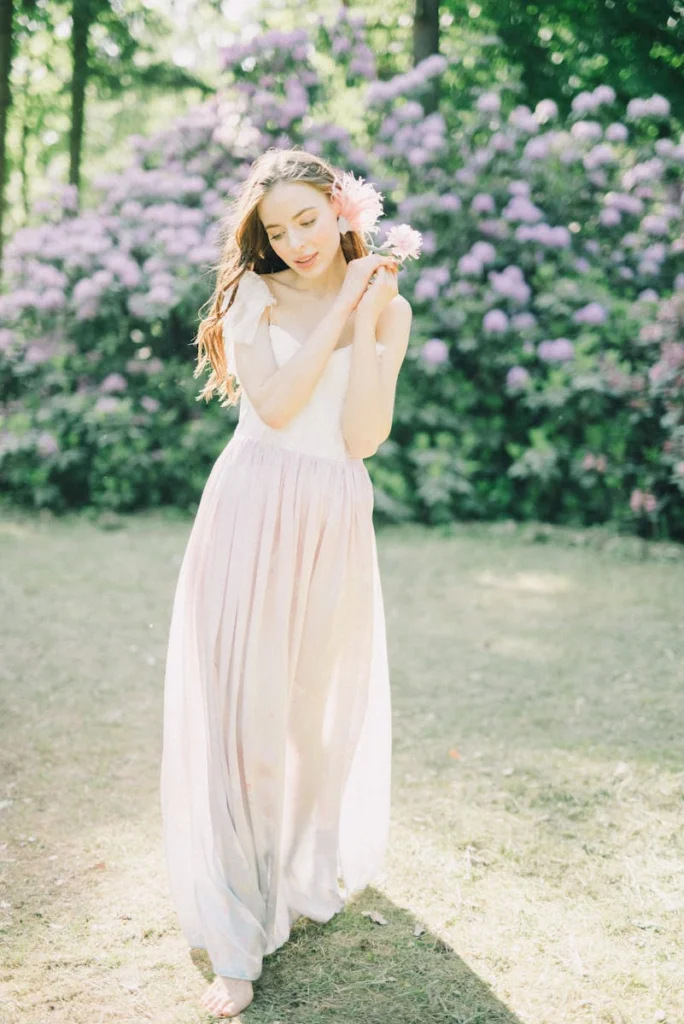 A young woman in a delicate dress enjoys a spring day in a blooming garden.