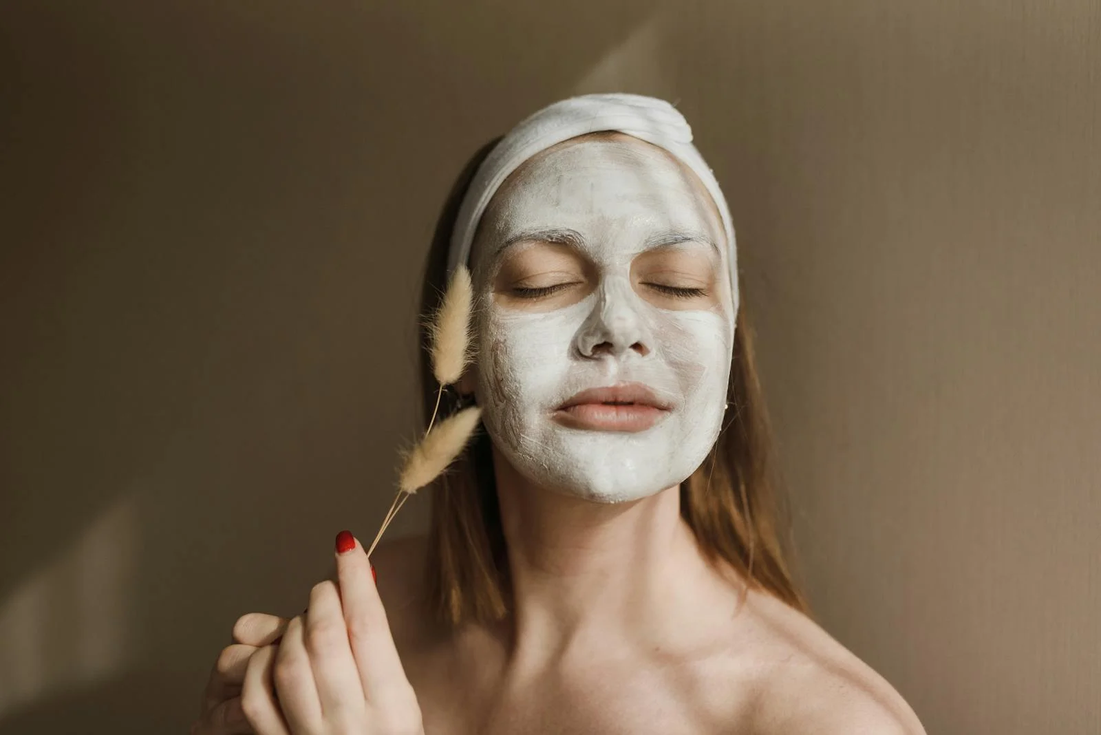 An adult woman enjoying a calming skincare session with a facial mask indoors.