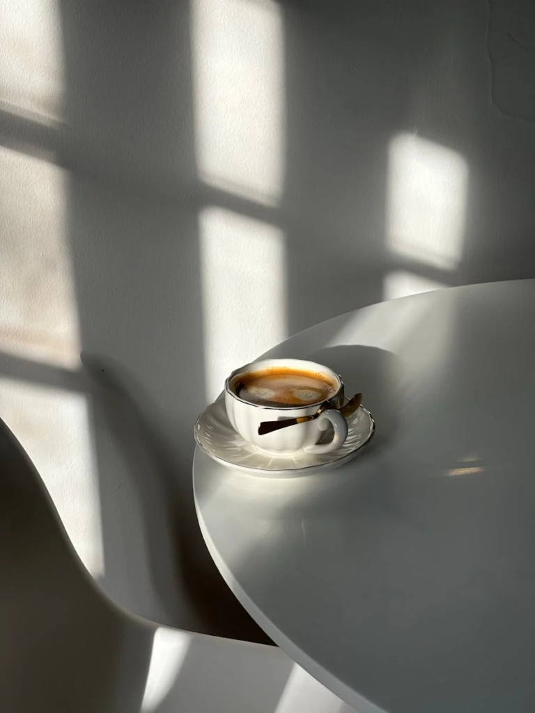 Elegant coffee cup casting shadows on a minimalist table, bathed in natural light.