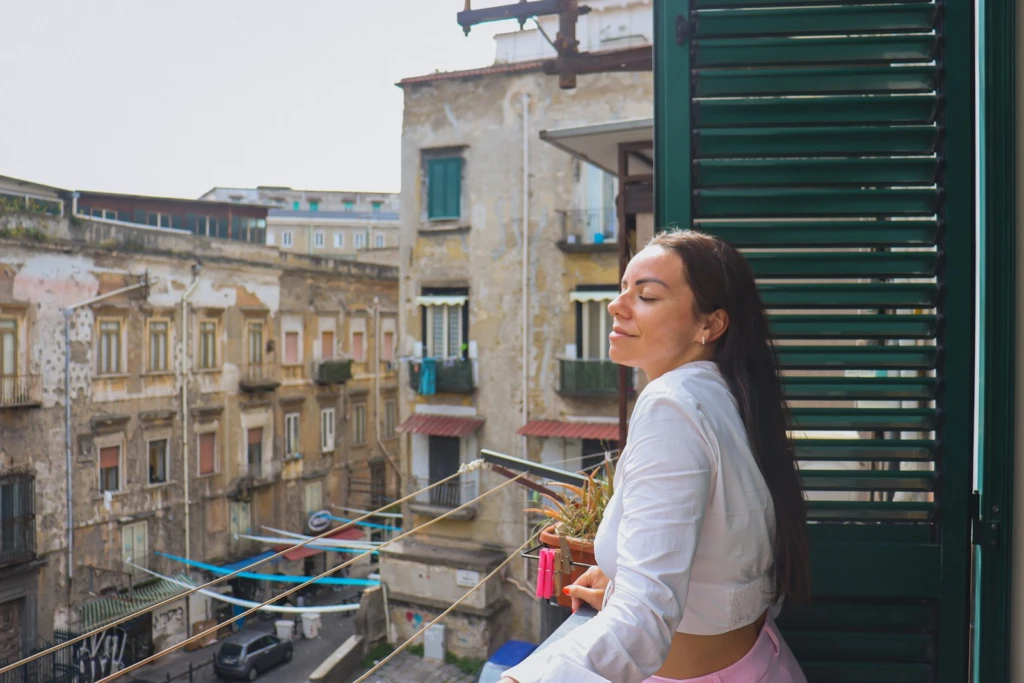 a woman standing on a balcony next to a building