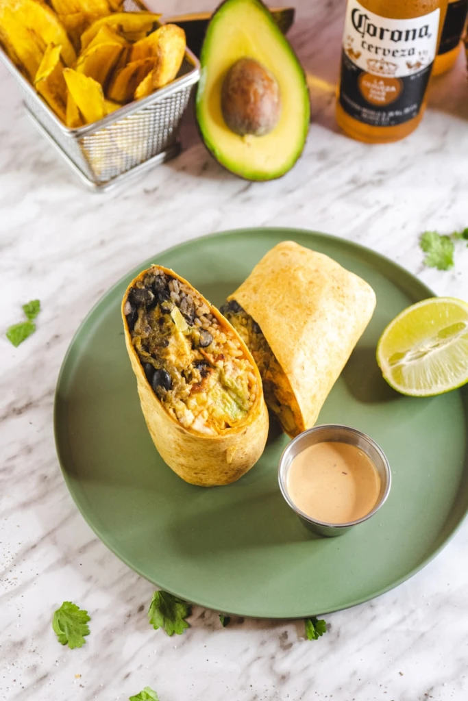 a green plate topped with a burrito and a cup of coffee