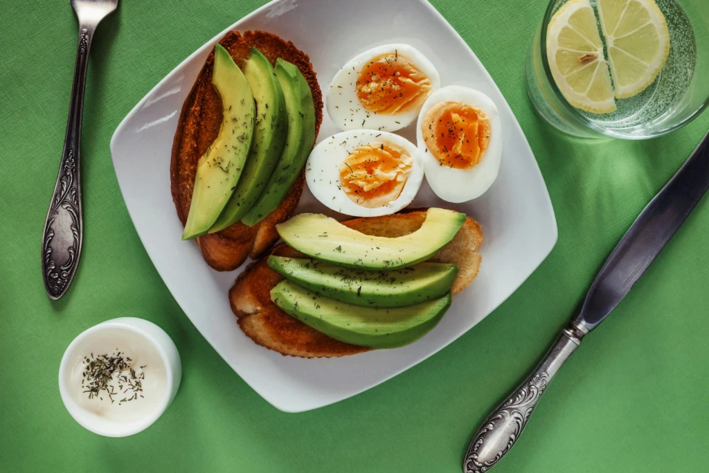 Sliced avocado on whole grain toast with eggs