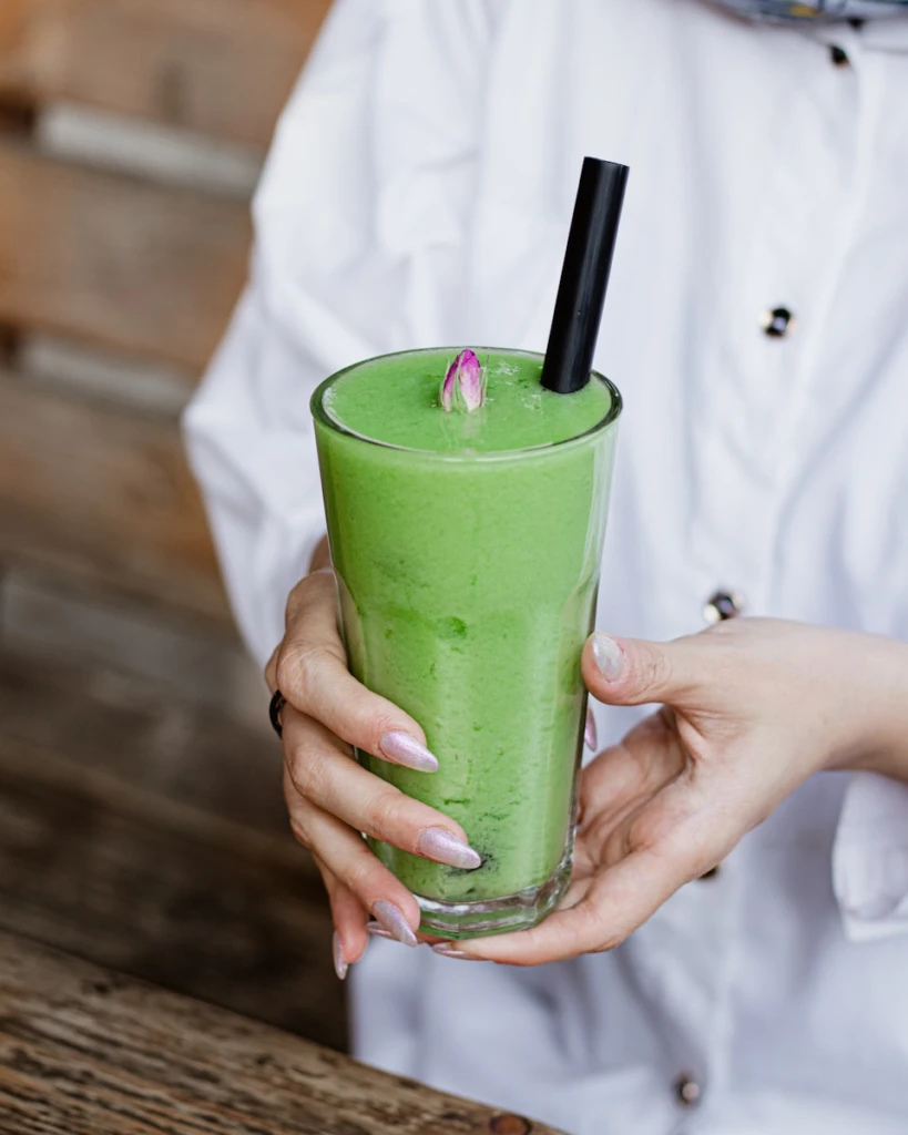 A woman holding a green drink in her hand