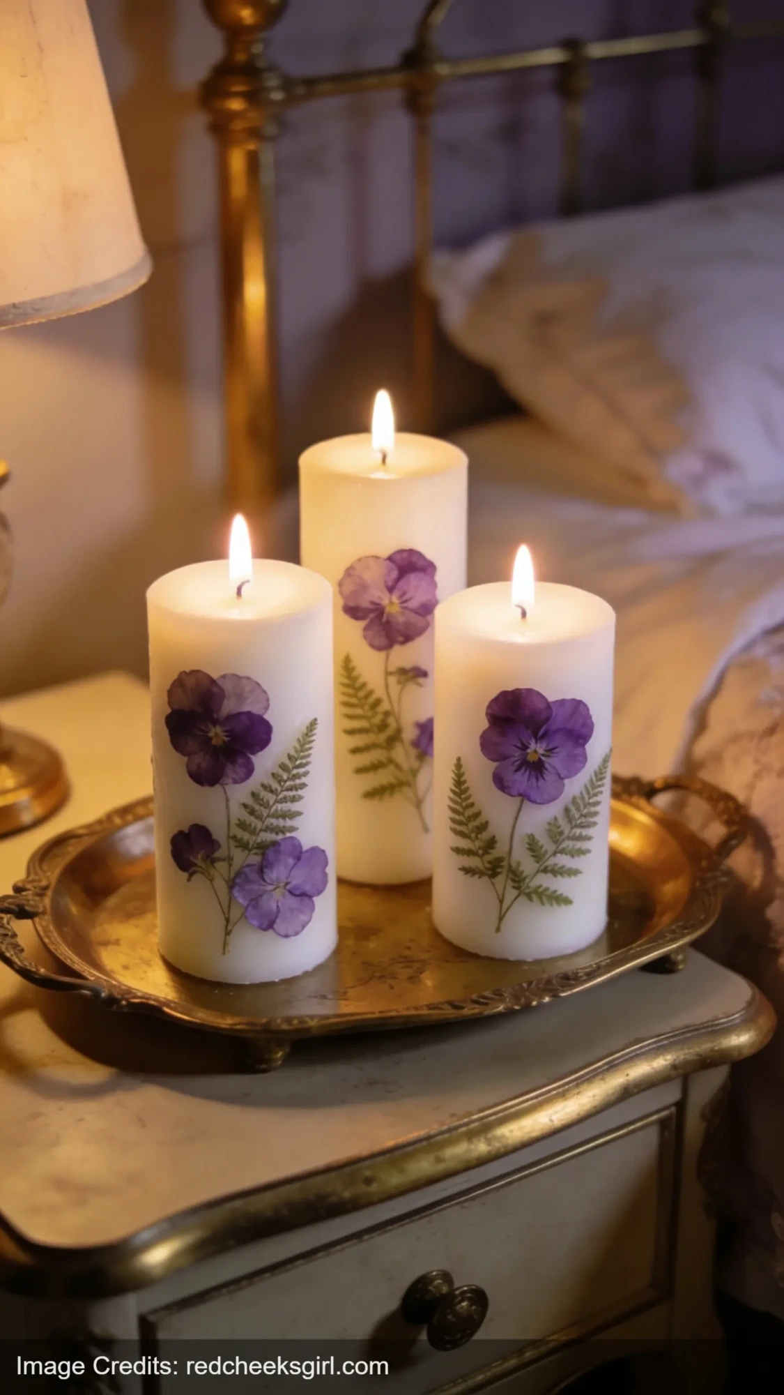 white pillar candles decorated with pressed flowers on brass tray