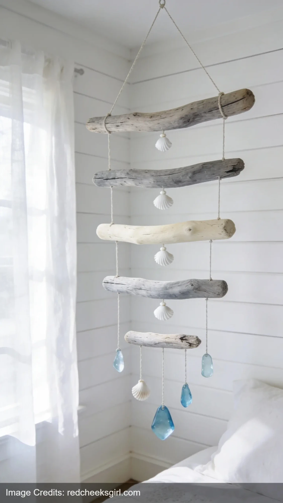 driftwood mobile with shells and sea glass hanging in coastal bedroom