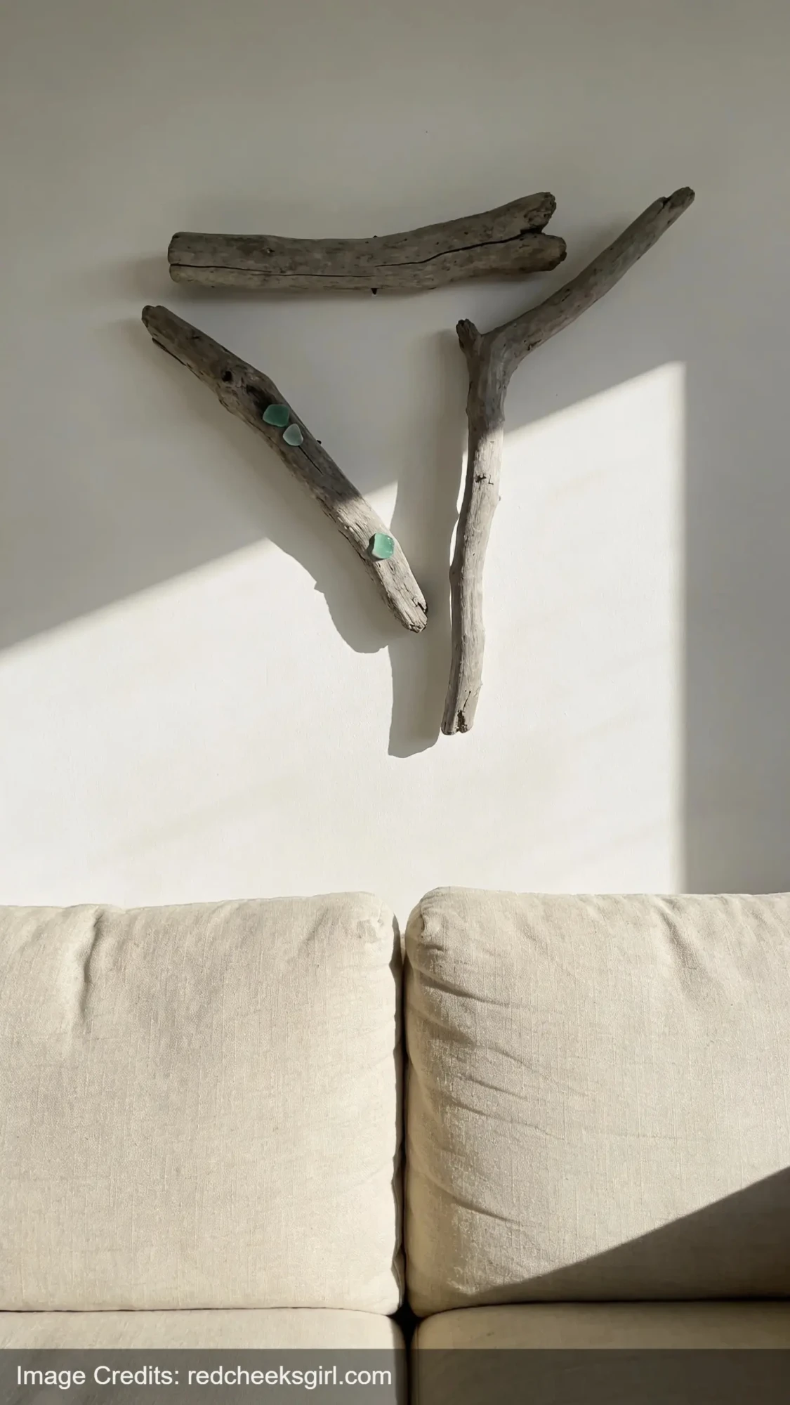 driftwood wall art arrangement with sea glass accents above sofa