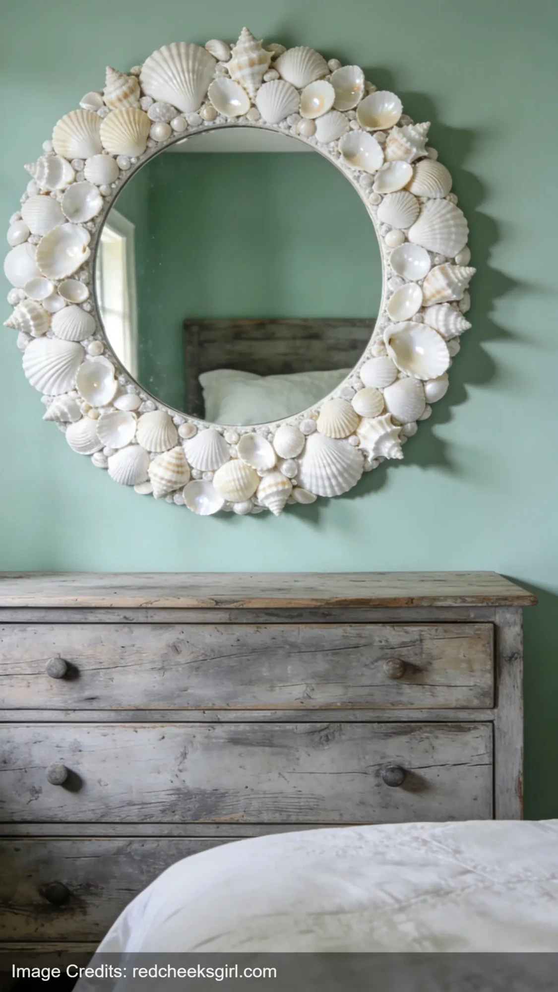 Handmade seashell mirror frame mounted on sage green wall for coastal bedroom decor