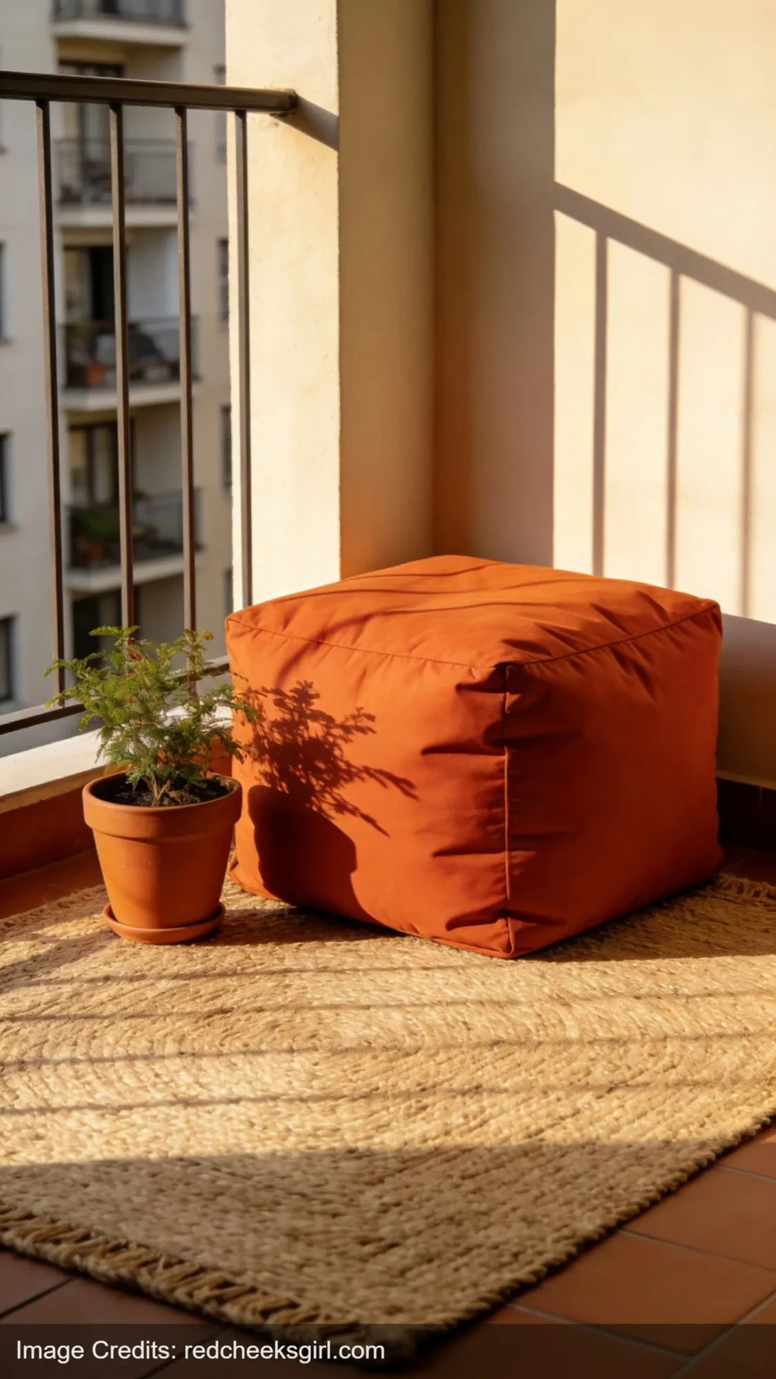 Burnt orange outdoor floor pouffe on jute rug creating cozy balcony seating area