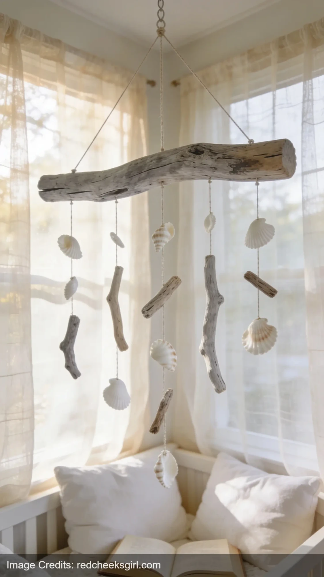 handmade driftwood mobile with shells hanging above cozy white reading nook