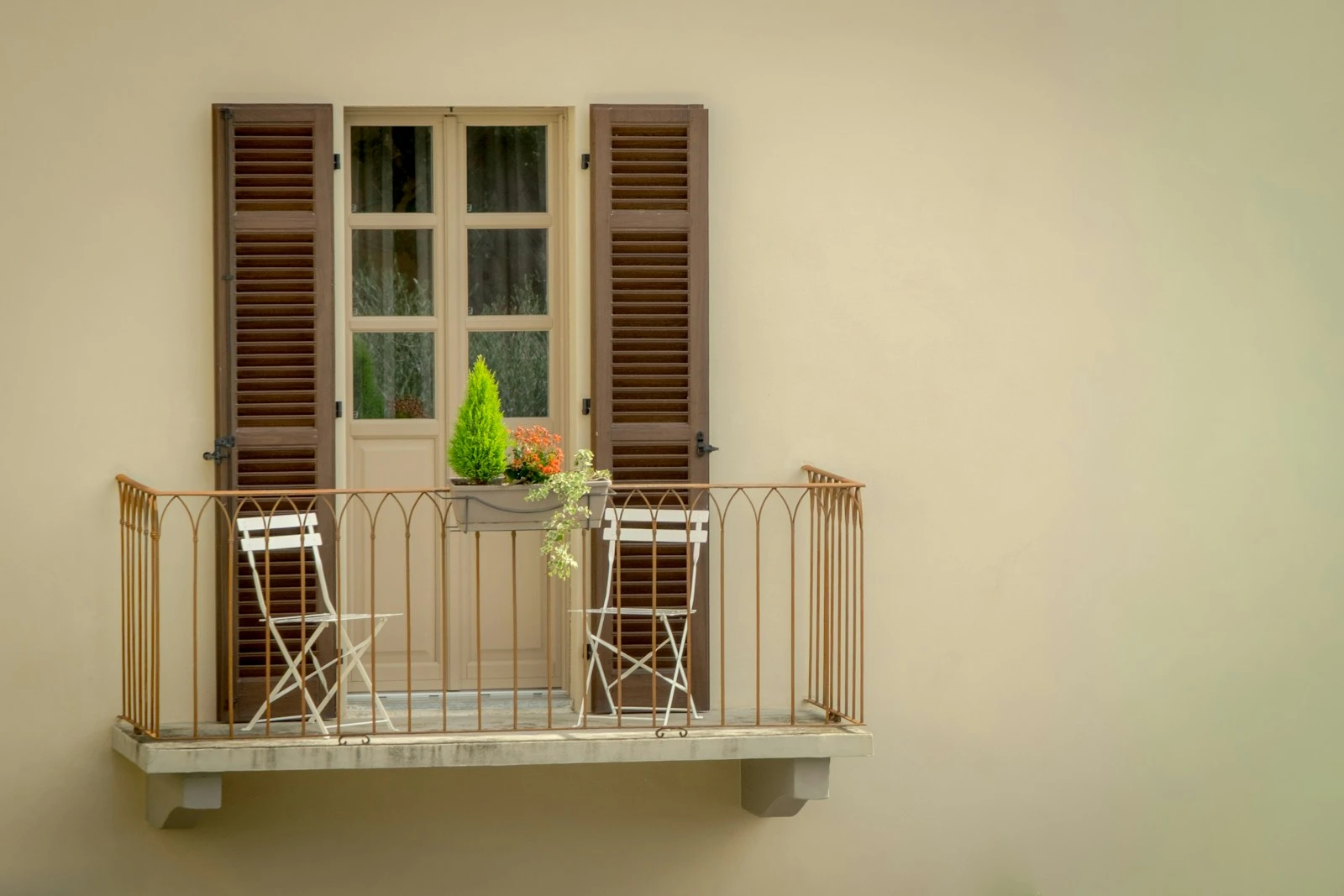 Balcony with chairs and a small tree.