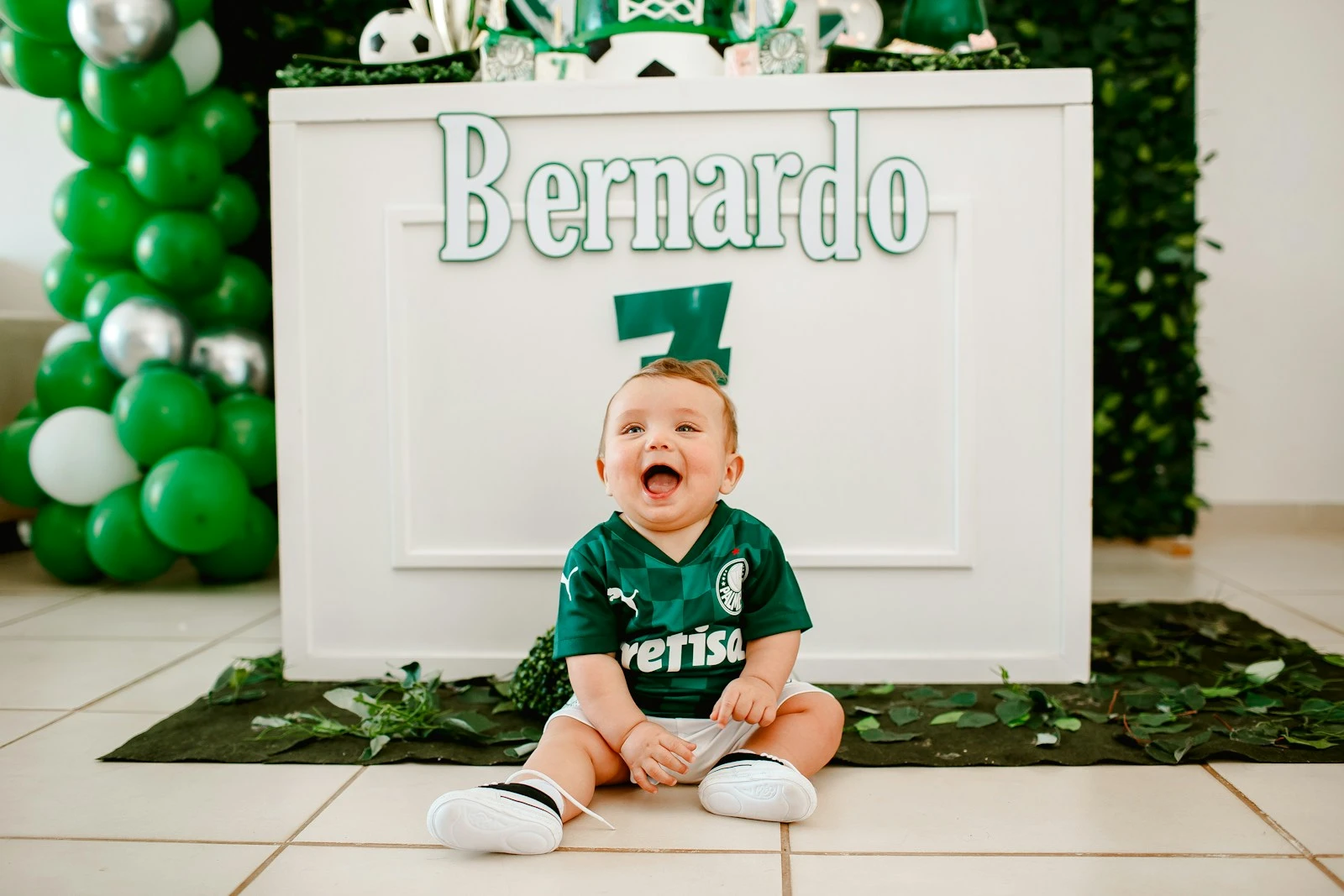 boy in green and white polo shirt sitting on white ceramic floor tiles