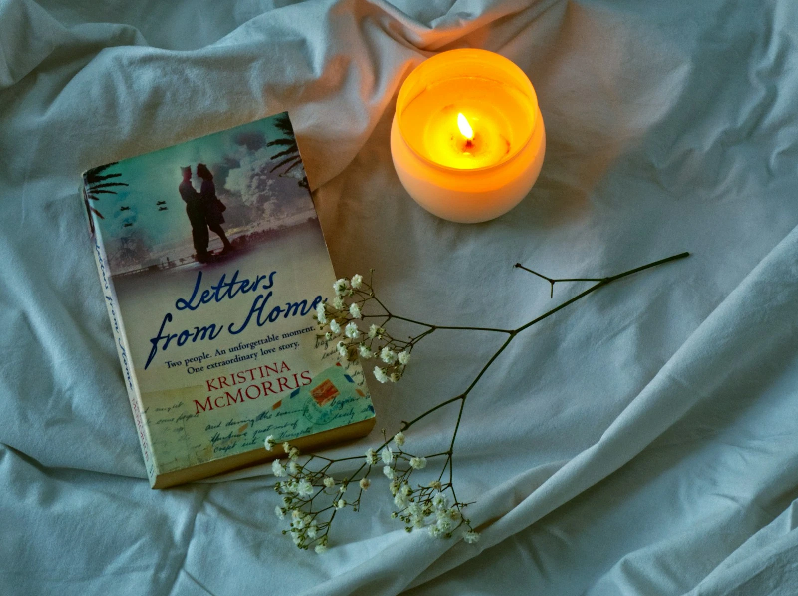 A book and a candle on a bed