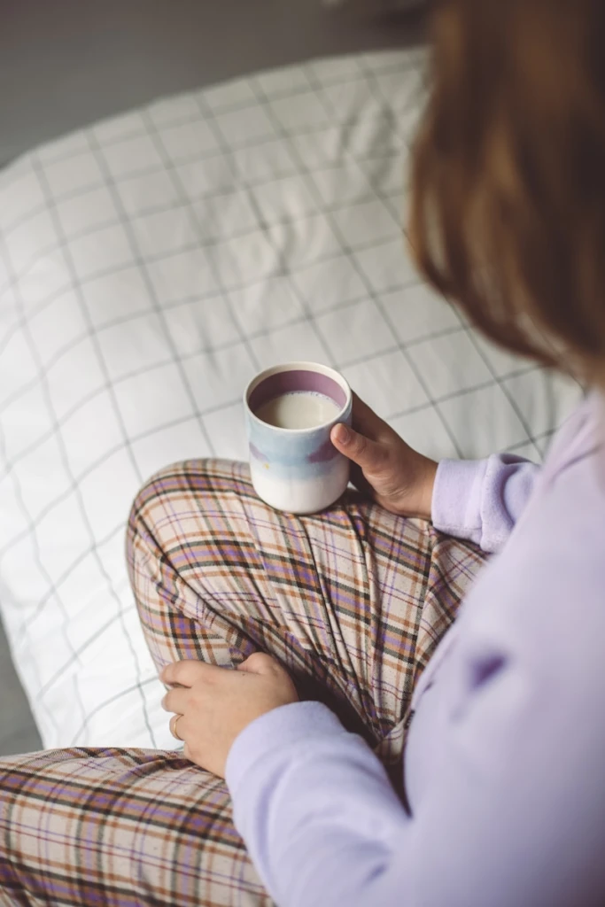 a woman sitting on a couch holding a cup of coffee
