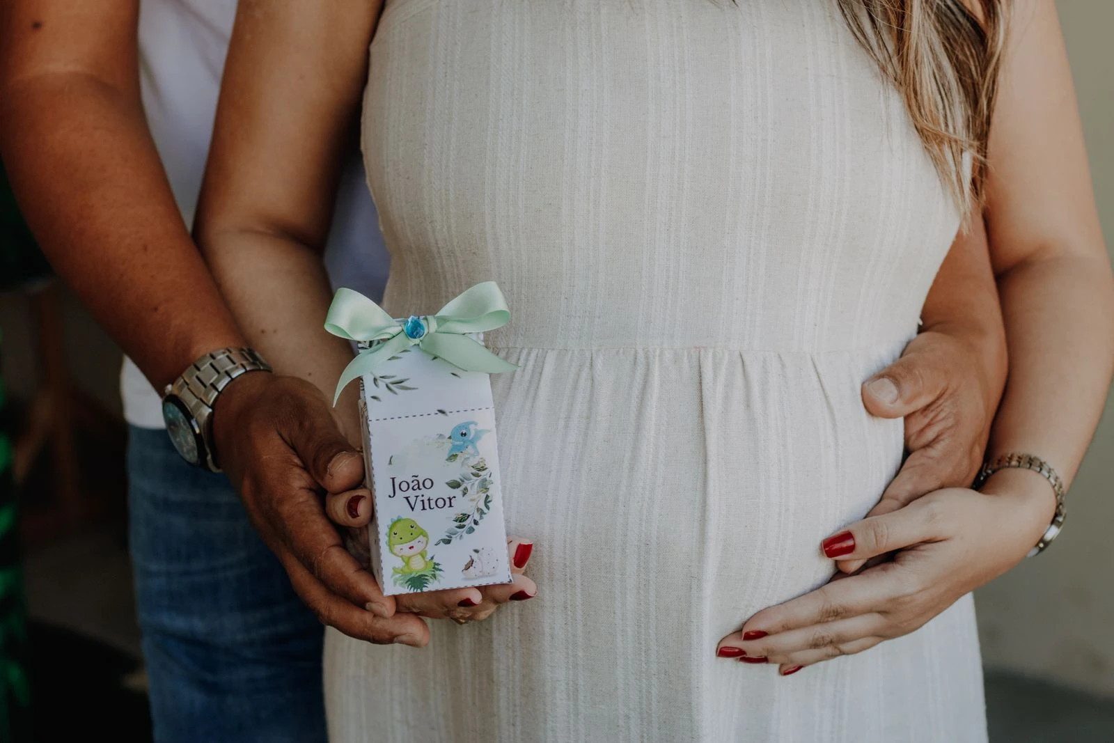 Pregnant couple sharing a tender moment, holding a personalized baby shower gift.