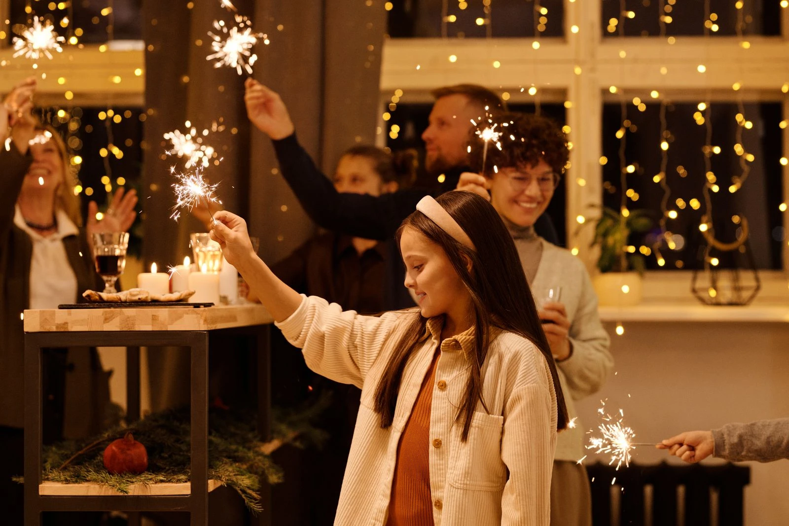 Family enjoying sparklers at an indoor celebration with warm holiday lighting.