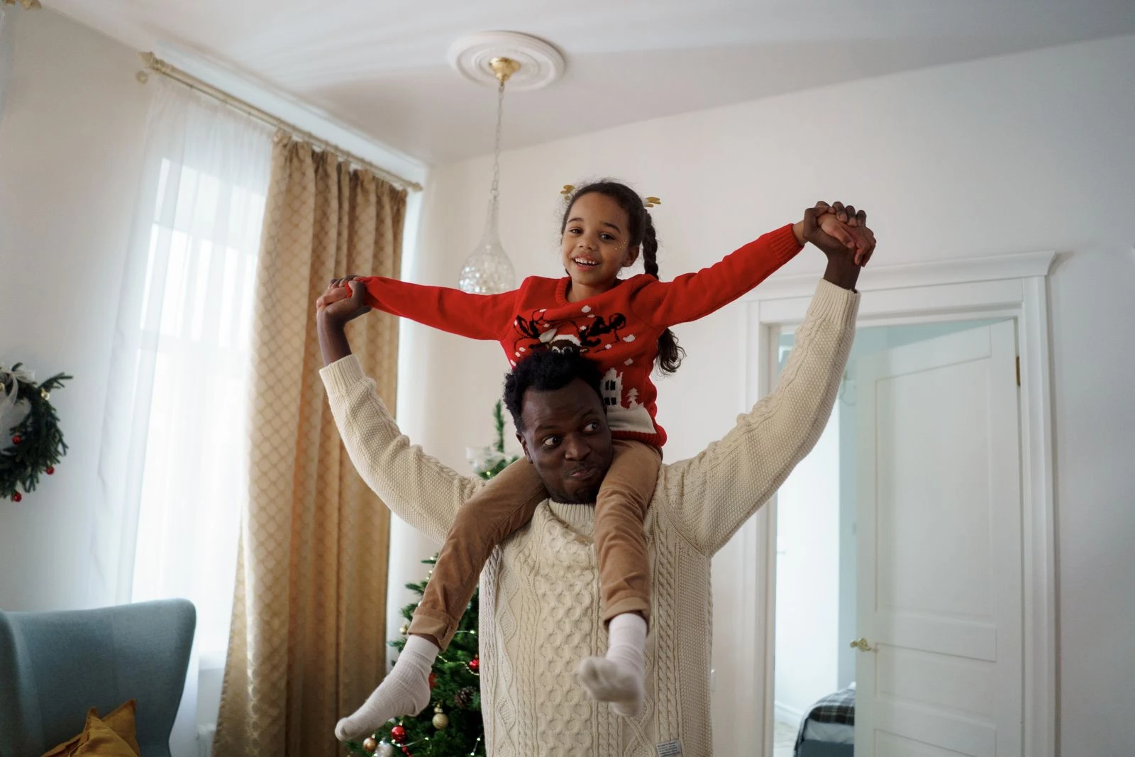 Cheerful father and daughter enjoying Christmas together indoors, spreading joy and love.