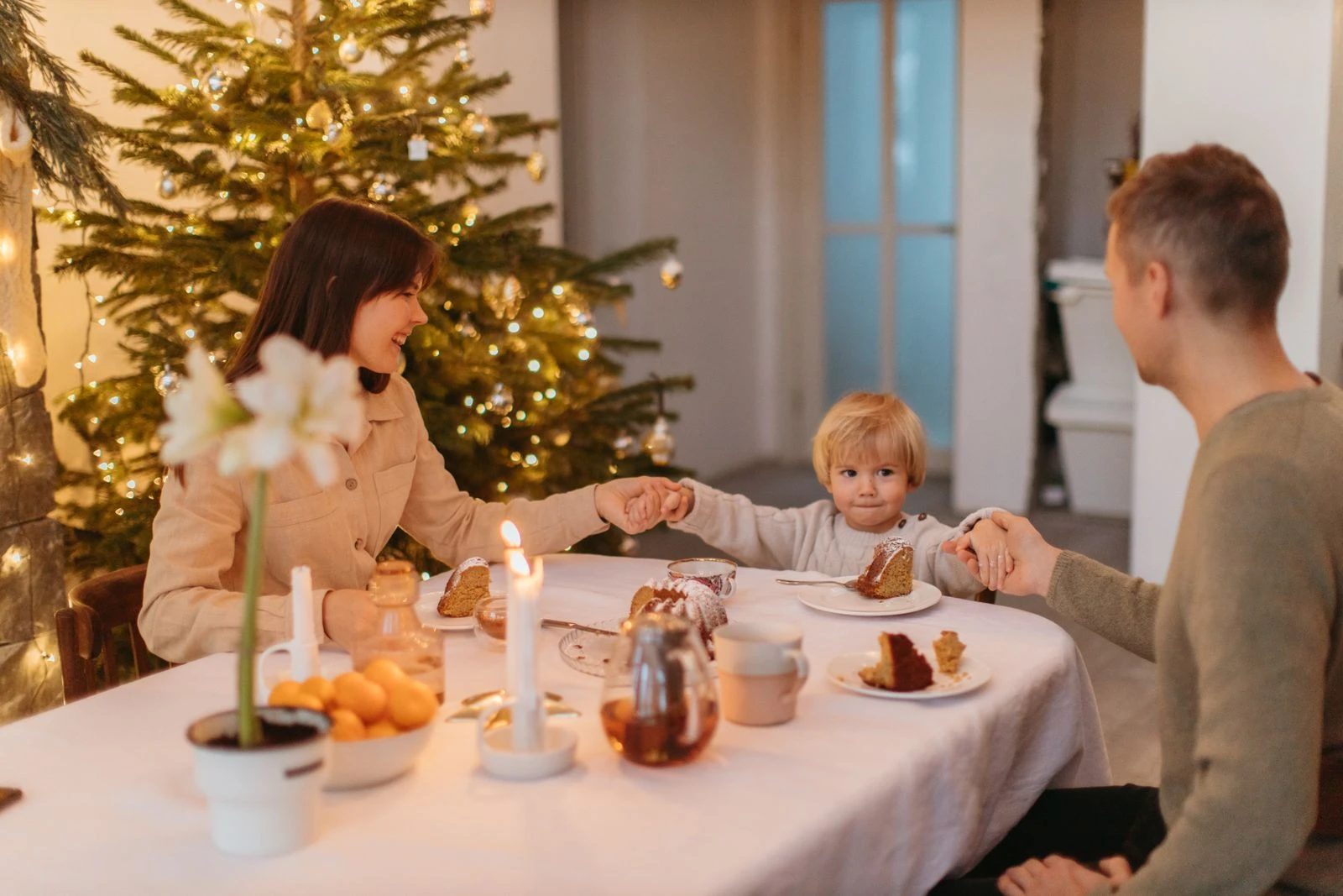 Family enjoying a festive meal by a Christmas tree, sharing love and togetherness.