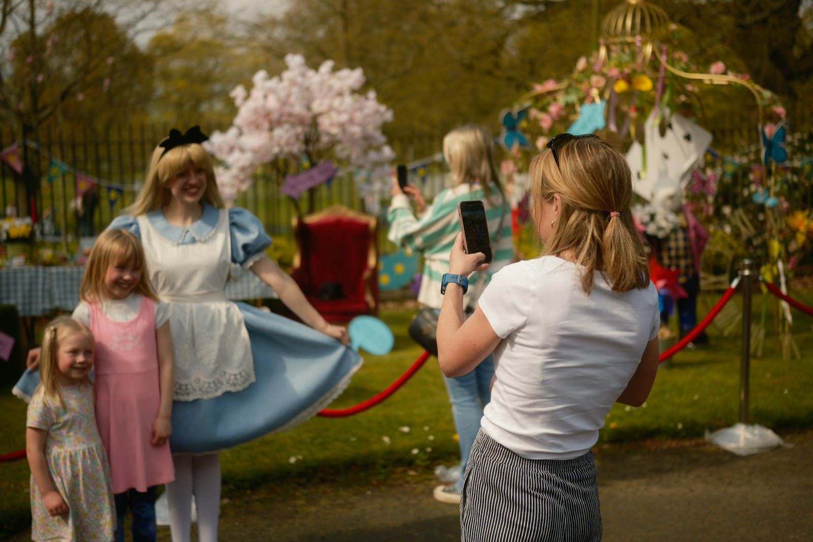Woman in alice costume poses with two children