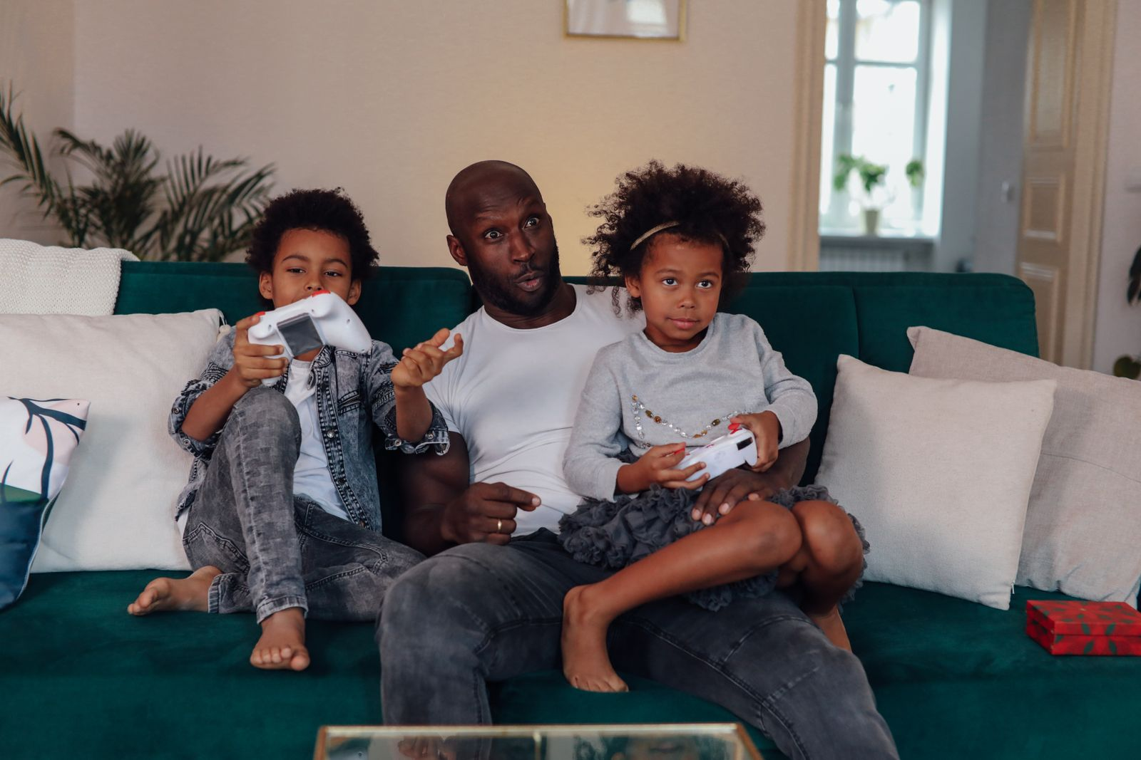 Father and children enjoying video games on the couch, capturing playful family quality time.