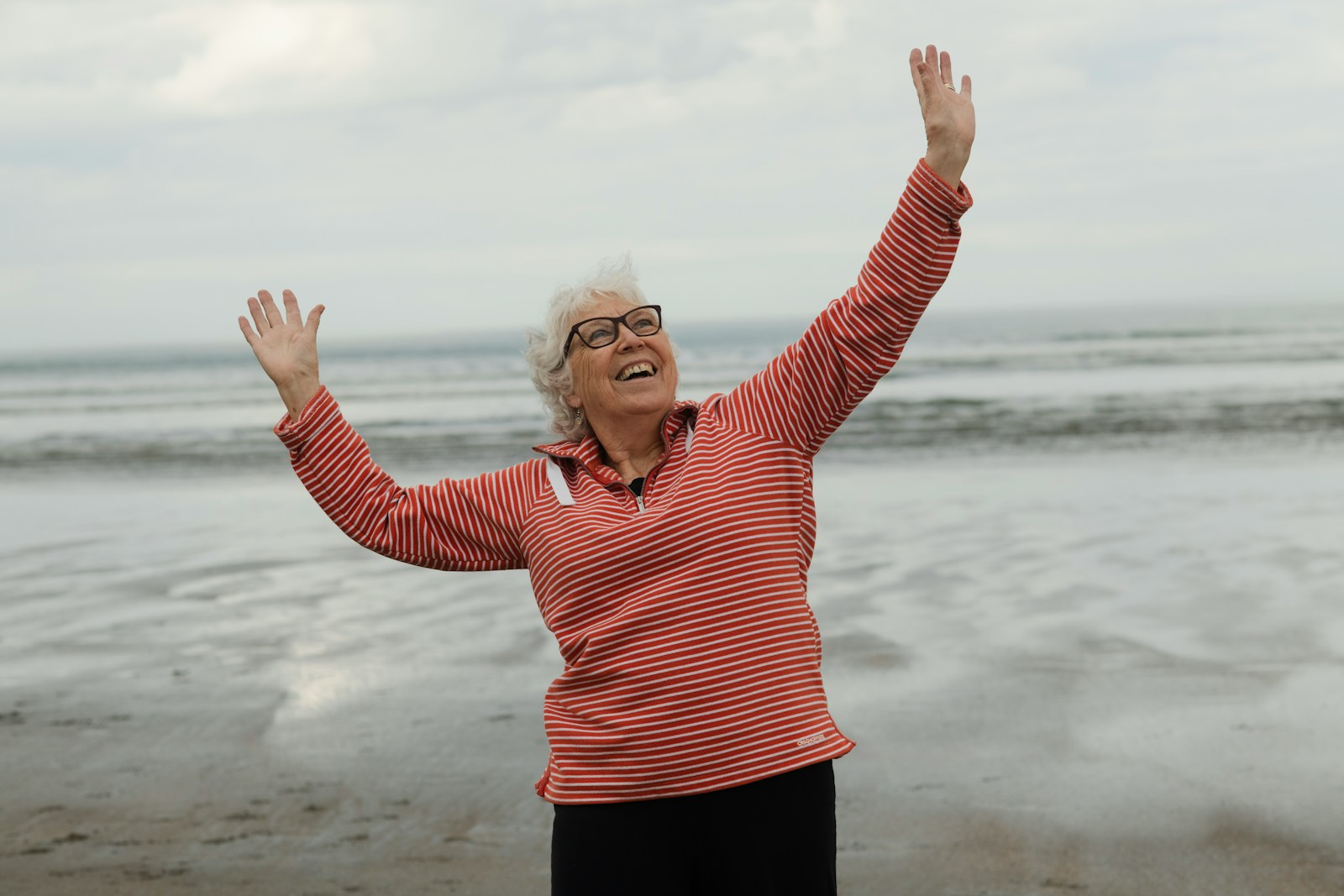 Woman raises arms on the beach with joy