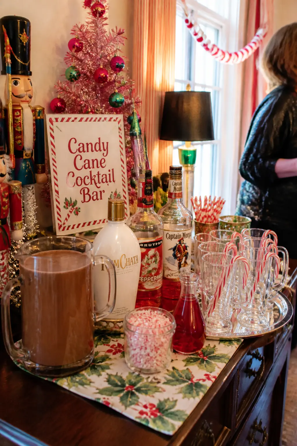 Candy Cane Cocktail Bar — A drinks station built around peppermint schnapps, white rum, and a jug of hot chocolate, with candy canes hooked over the rim of