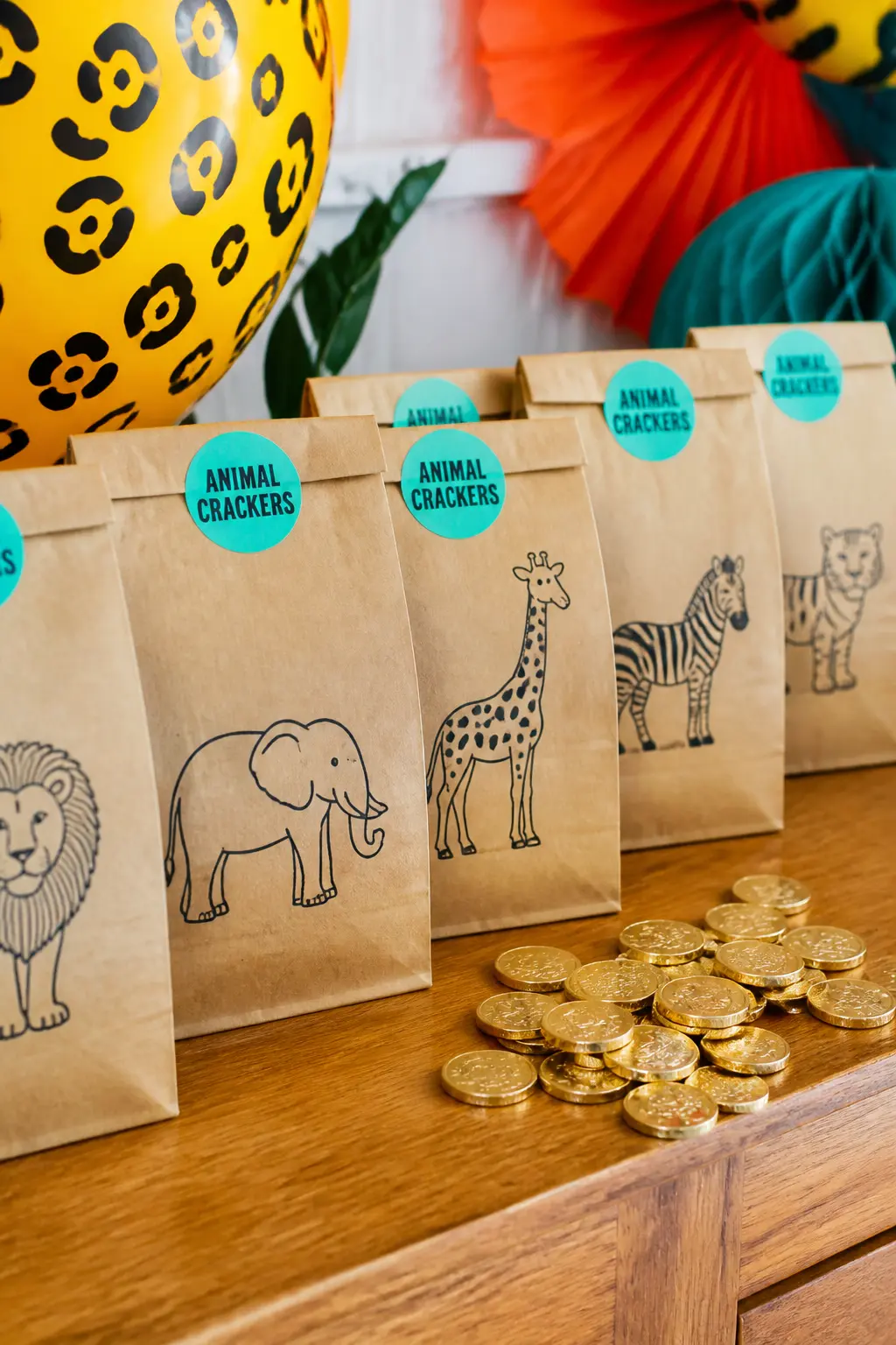 Animal Cracker Favour Bag — A kraft paper bag printed with animal outlines, filled with a small box of animal crackers, a chocolate coin wrapped in gold foil