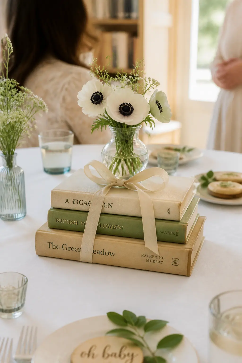 Three-Tier Book Stack Centrepiece with Bud Vase — Stack three hardbacks of diminishing size, spines facing the same direction, in the centre of each table.