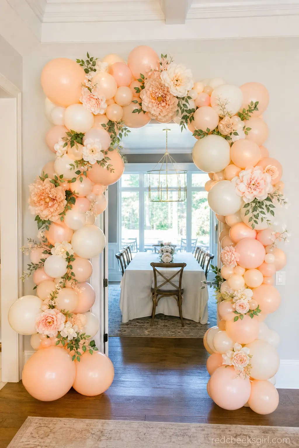 Peach and Ivory Balloon Arch — A balloon arch in warm peach and ivory, threaded with a few oversized paper or silk blooms, frames a doorway or the top of the
