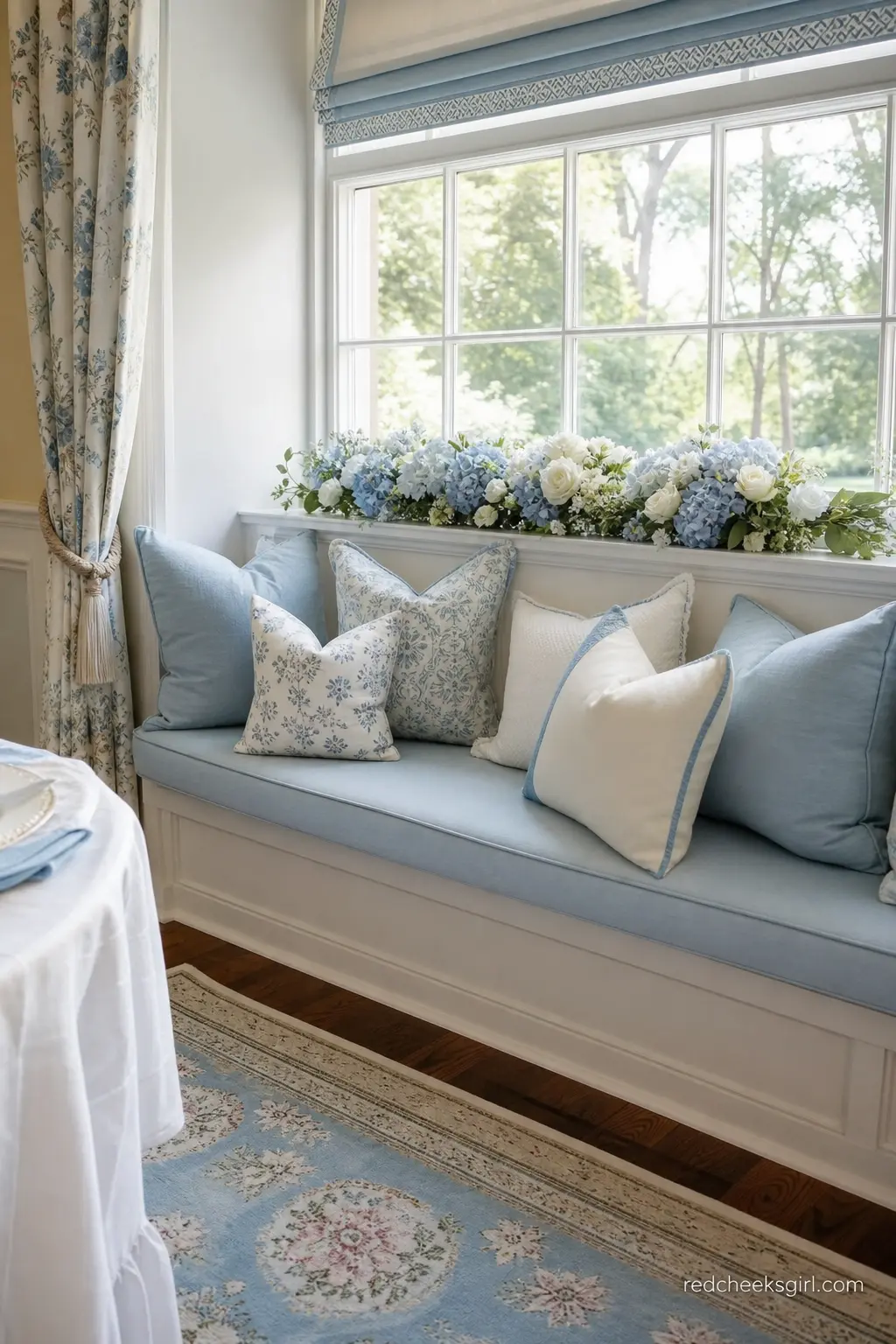 Sky Blue and Ivory Window Nook — A window seat or armchair corner dressed with sky blue and ivory cushions and a low arrangement of blooms on the sill becomes