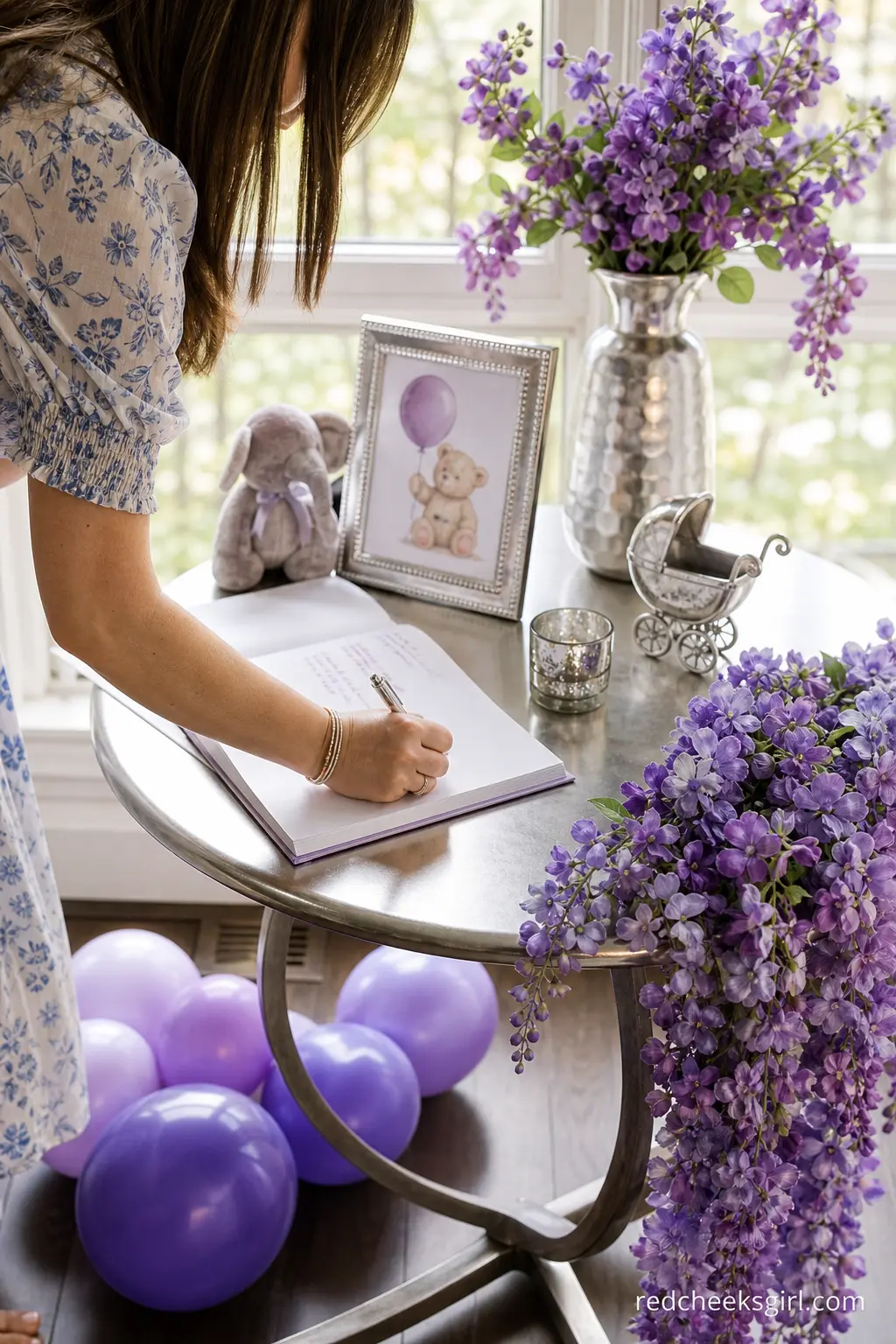 Wisteria and Silver Guest Book Table — A small side table holding an open guest book, dressed with a trailing arrangement of wisteria purple blooms and a few