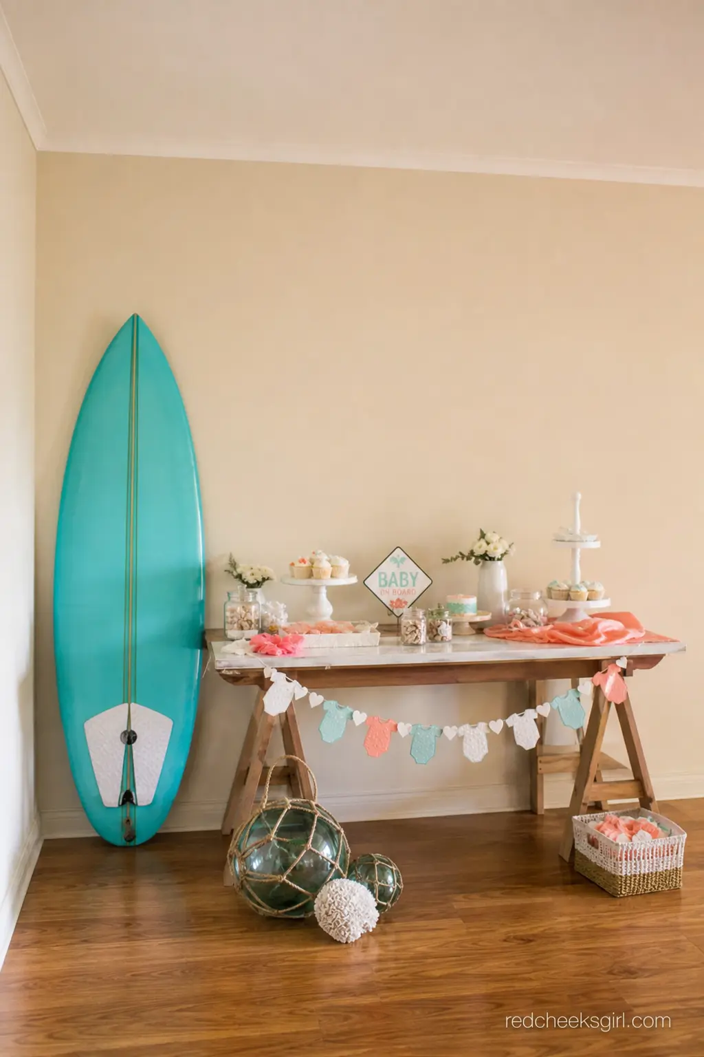 Surfboard Dessert Backdrop — A single mini surfboard leaned against the wall behind the dessert table covers the whole surf angle of the theme without a full