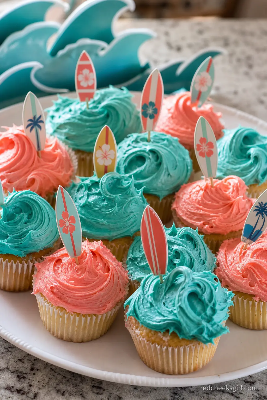 Wave Cupcakes with Surfboard Toppers — Coral and teal buttercream piped into a wave shape turns an ordinary cupcake into a tiny beach scene, and a painted