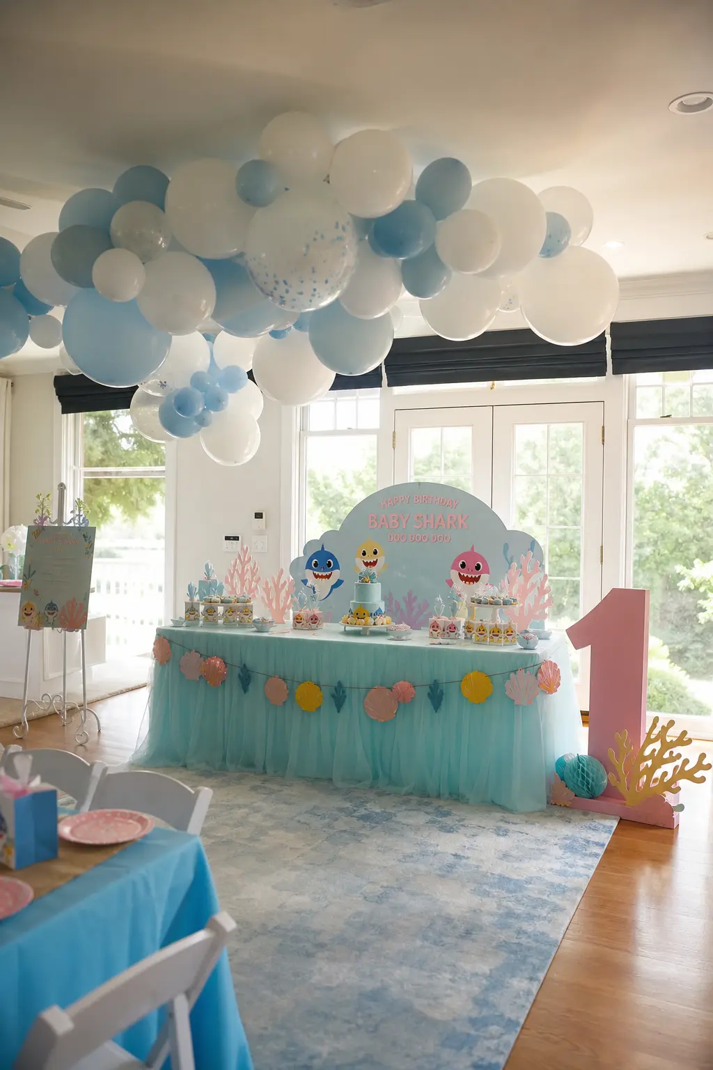 Balloon Cloud Ceiling Installation — A loose cluster of pale blue and white balloons, floated and tethered just above the dessert table, gives the room height