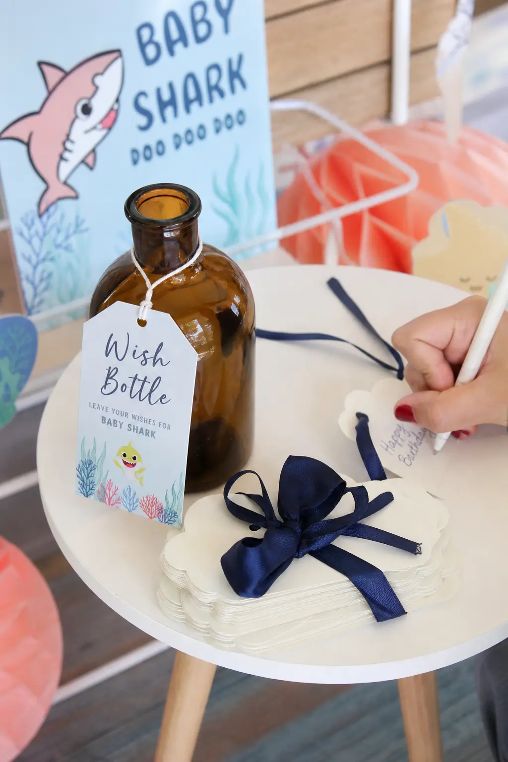 Wish Bottle Guest Book Alternative — An amber glass bottle beside a small stack of cream cards, tied with navy ribbon, replaces the guest book entirely. Baby
