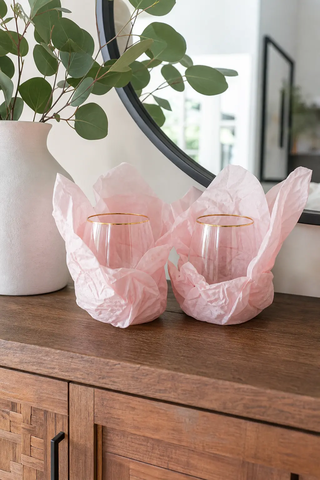 Stemless Wine Glasses Wrapped in Tissue — A pair of stemless wine glasses with a thin gold rim reads as a real gift rather than a party favor, and stemless