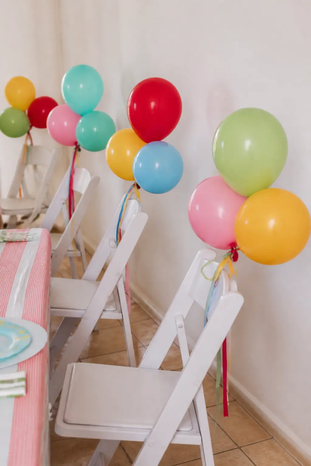 Cluster of Balloons Tied to Each Chair — Tie a cluster of three 11-inch balloons, one primary and two pastels, to the back of each dining chair. Fun to be one