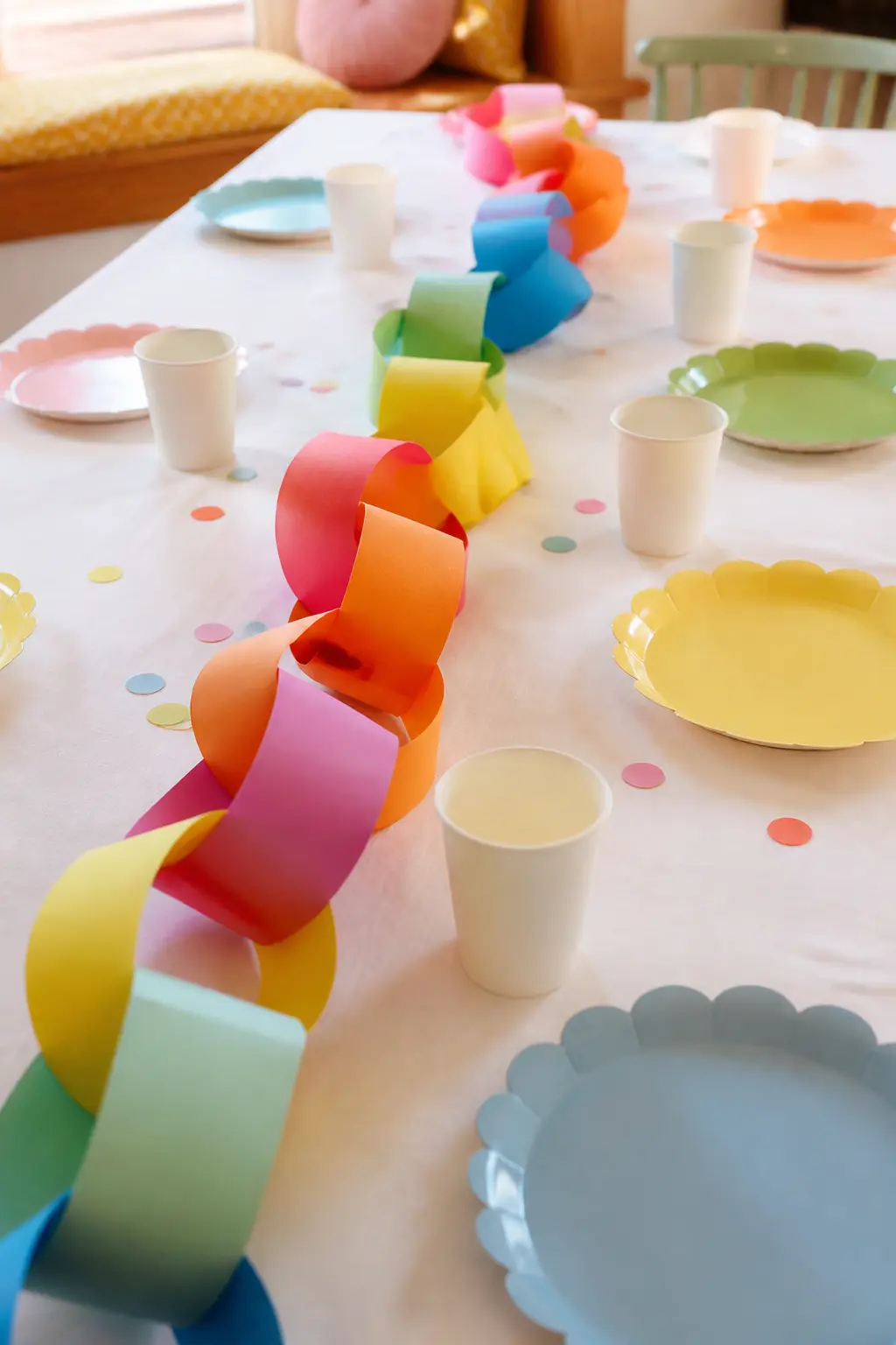 Paper Chain Table Runner — A paper chain made from strips of cardstock in a fixed colour sequence runs down the centre of the table instead of a fabric runner.