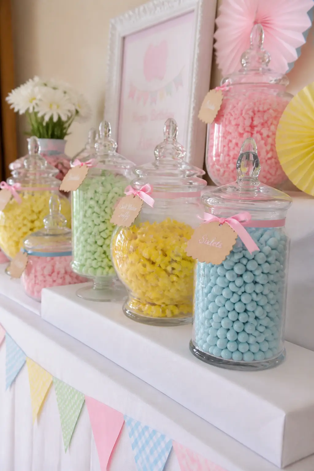 Candy Bar in Pastel Jars — Six to eight apothecary jars filled with pastel candies, each jar labelled with a small hand-written tag tied with a thin satin