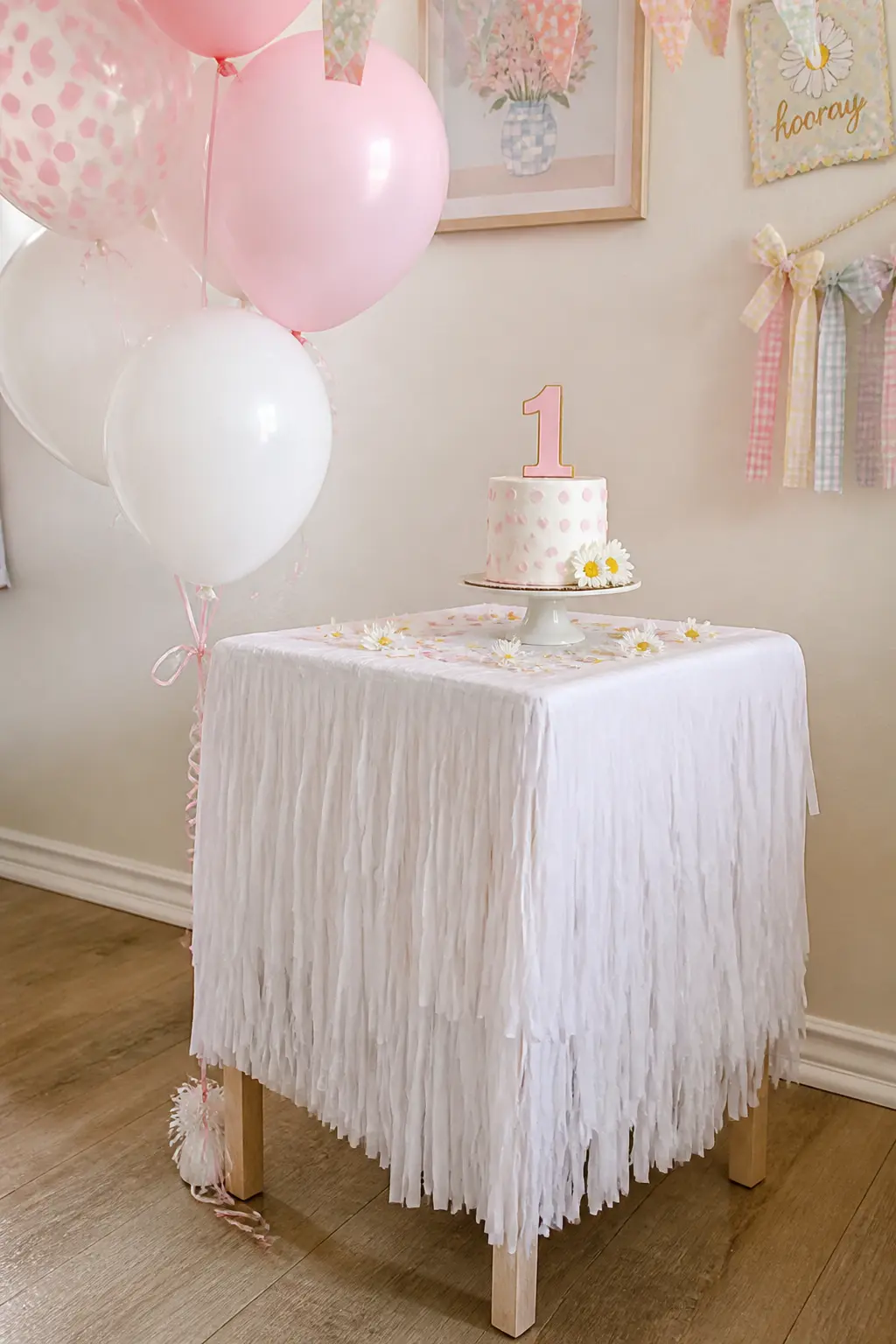Smash-Cake Station with Fringe Skirt — A small side table pulled away from the wall, skirted in a white tissue-paper fringe skirt and topped with a single cake