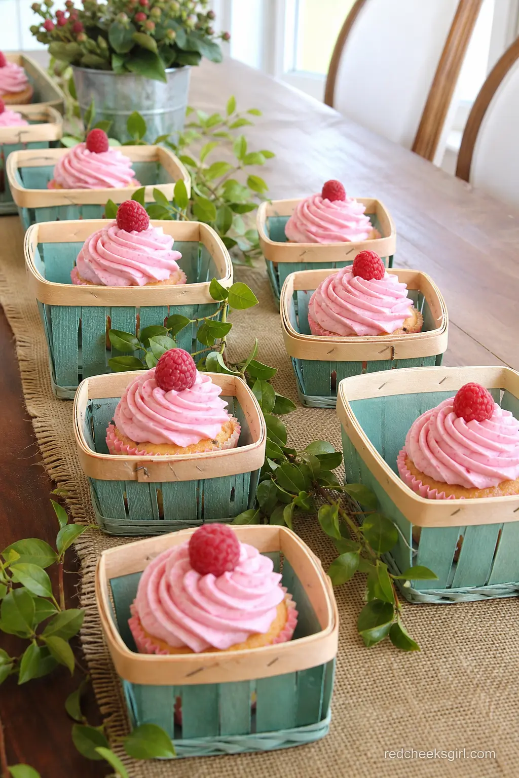 Berry Basket Cupcake Display — Nest raspberry pink frosted cupcakes into small wicker berry baskets down a long wooden table. Berry sweet baby shower theme