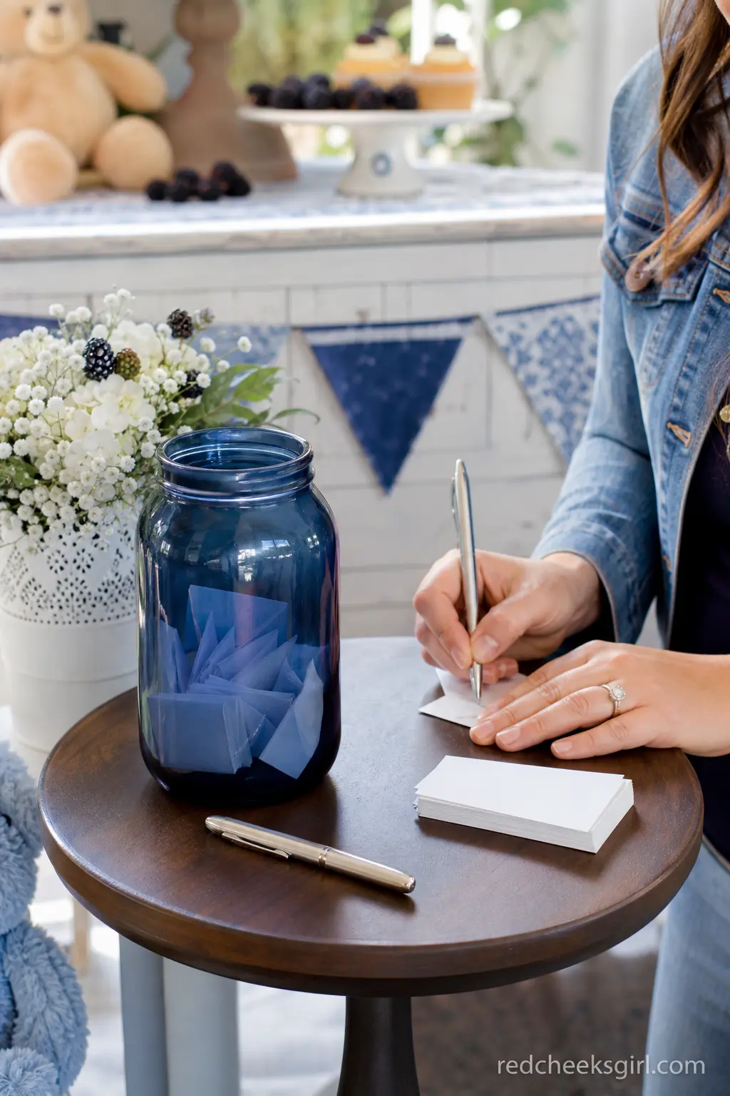 Wishes for Baby Jar Station — A midnight blue glass jar half filled with folded note cards gives guests a quiet activity near the exit. Berry sweet baby shower