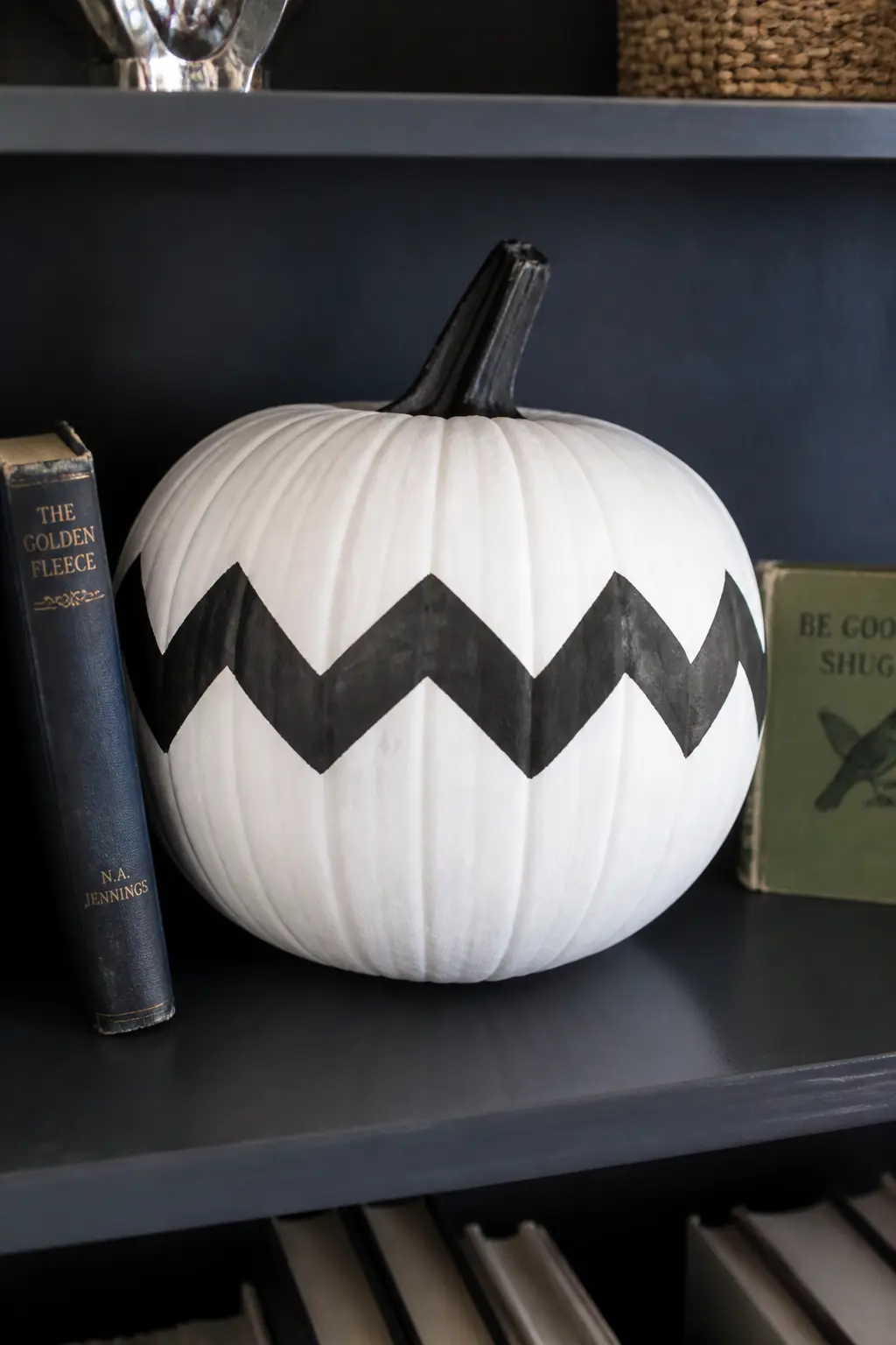 Chevron Around the Middle — Find the midpoint of the pumpkin and tape a zigzag band roughly five centimetres deep around its equator. Black and white painted