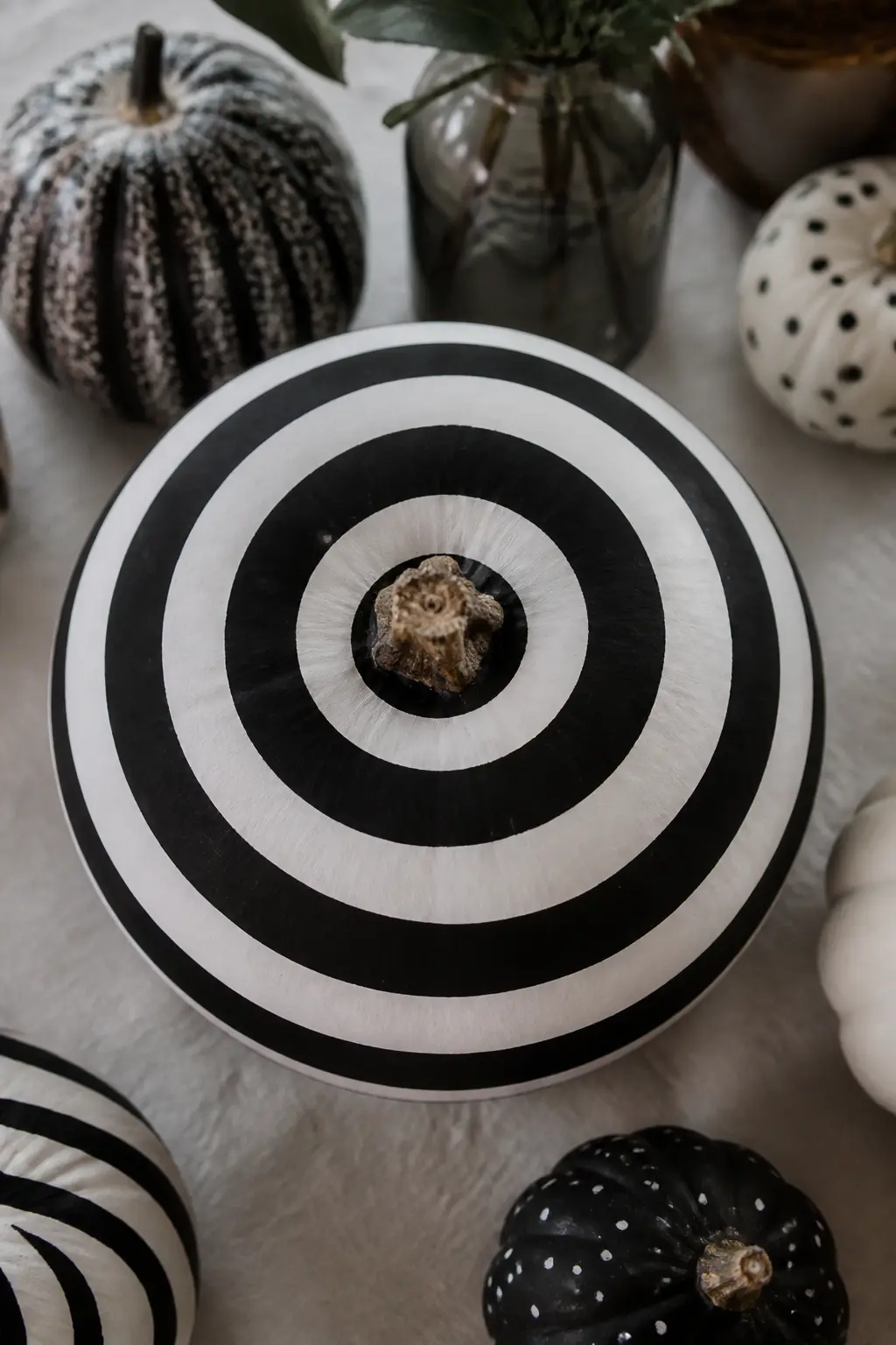 Concentric Rings from the Top — Starting at the stem, tape and paint concentric rings radiating outward and downward. Black and white painted pumpkin