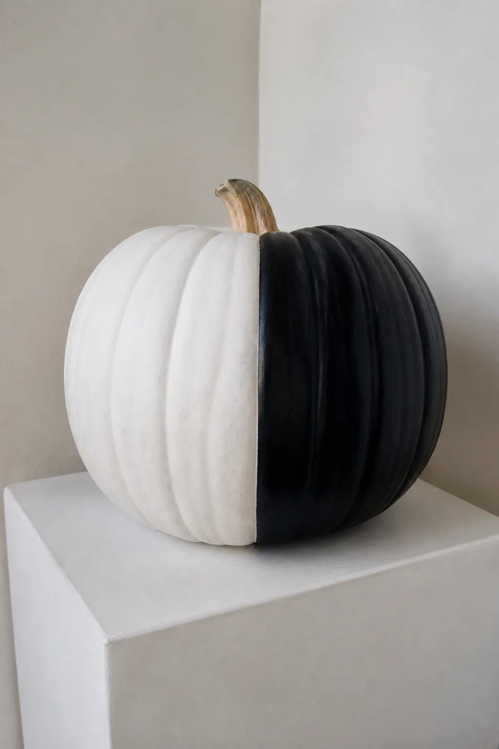Half Black, Half White Down the Vertical — Tape a single vertical line from stem to base, dead centre. Black and white painted pumpkin