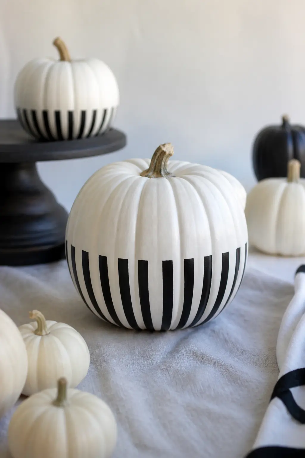 Stripes Only on the Lower Half — Keep the upper half plain white and run black stripes only across the bottom half of the pumpkin, finishing at the natural