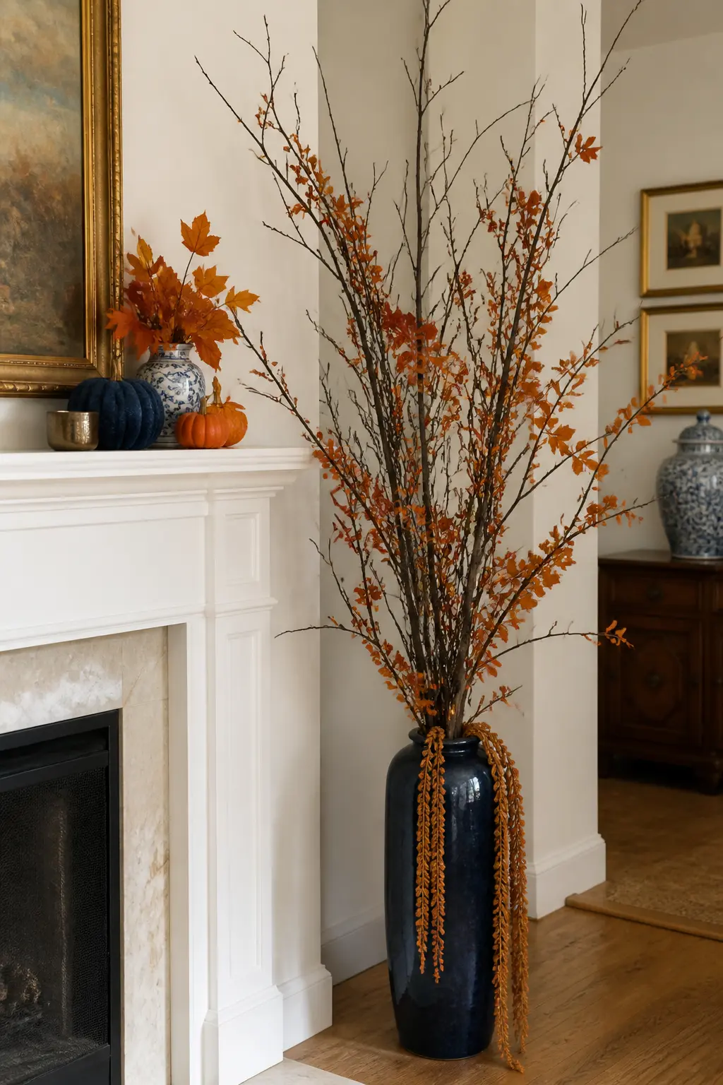Blue and Orange Branch Arrangement in a Tall Blue Vase — A single tall arrangement in a navy or cobalt vase placed on the floor beside a fireplace or at the