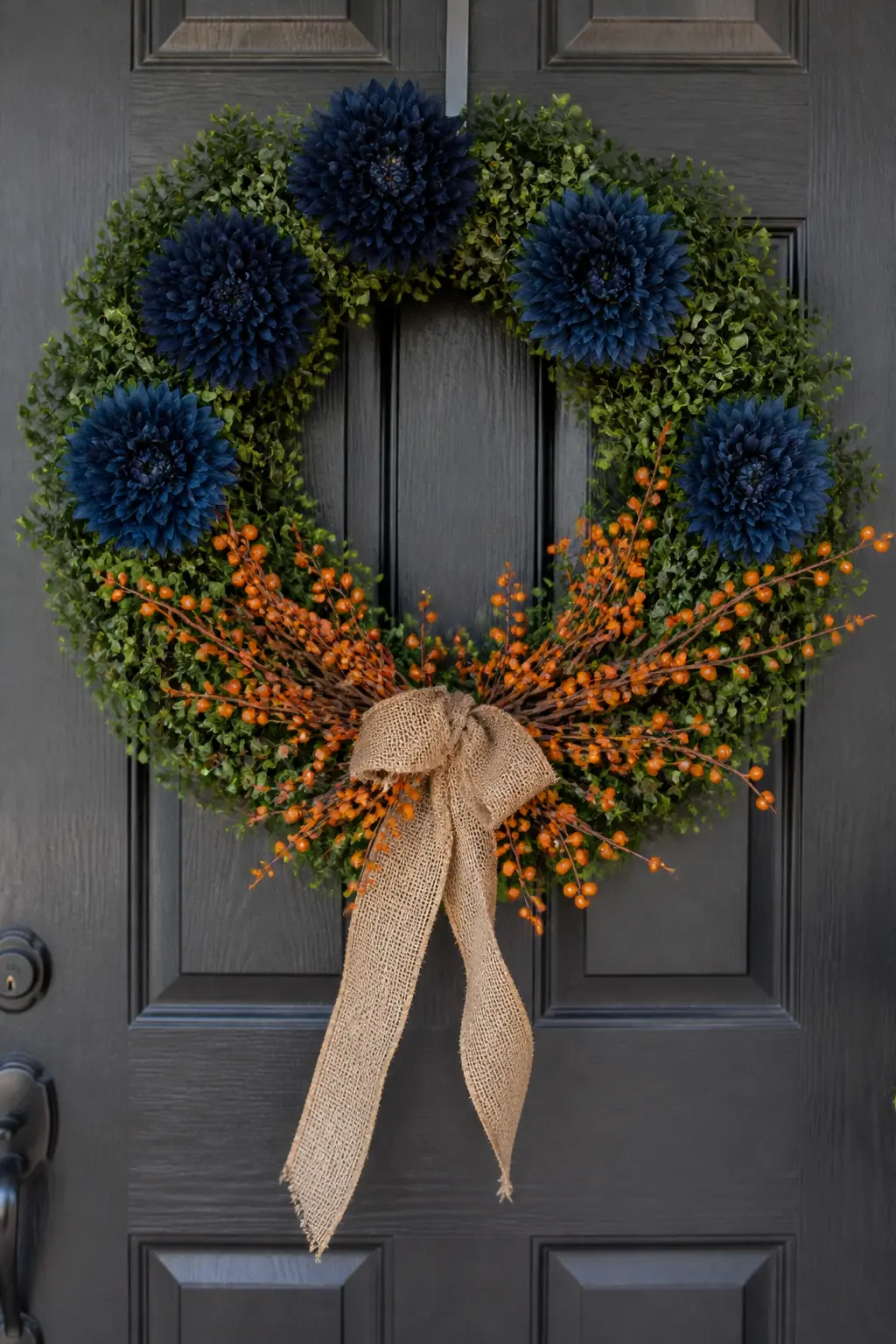 Navy Mum and Orange Berry Boxwood Wreath — A faux boxwood base gives the wreath a year-round starting point. Blue and orange fall decor