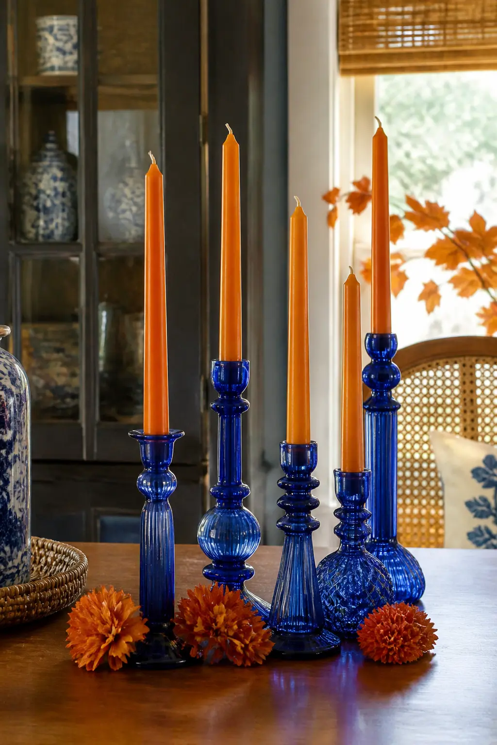 Orange Taper Candles in Blue Glass Holders — This works as a centrepiece on its own or paired with any of the other table ideas. Blue and orange fall decor
