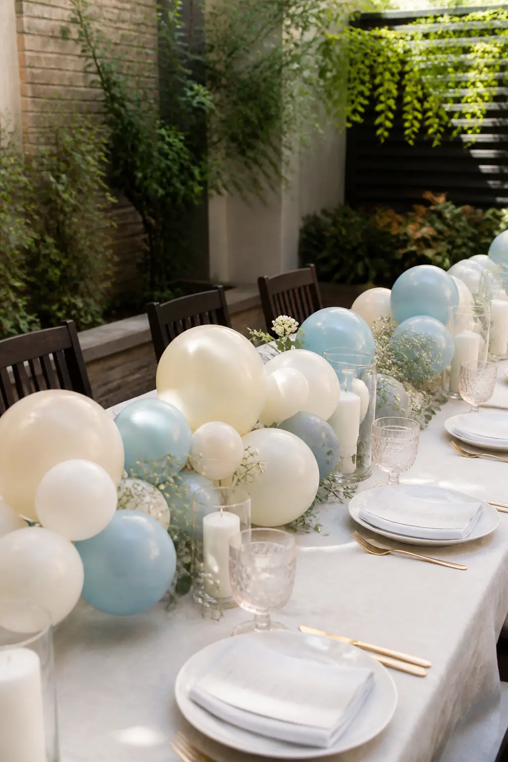 Cream and Dusty Blue Low Garland Down an Outdoor Lunch Table — A low cream and dusty blue garland runs the full length of a rectangular outdoor lunch table